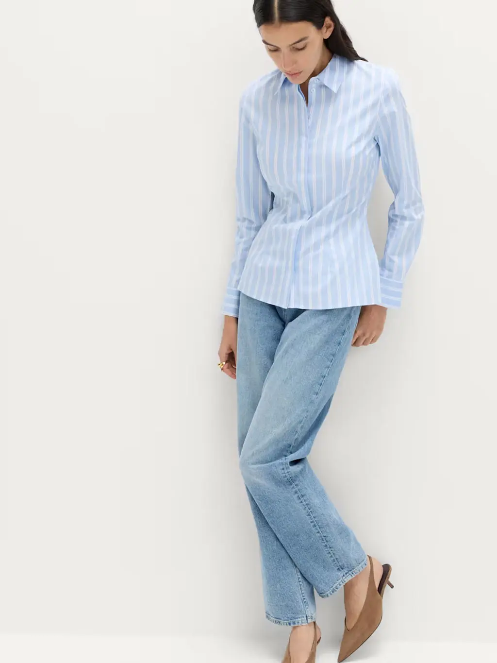 Woman wearing a blue and white striped shirt with blue jeans and brown suede heels