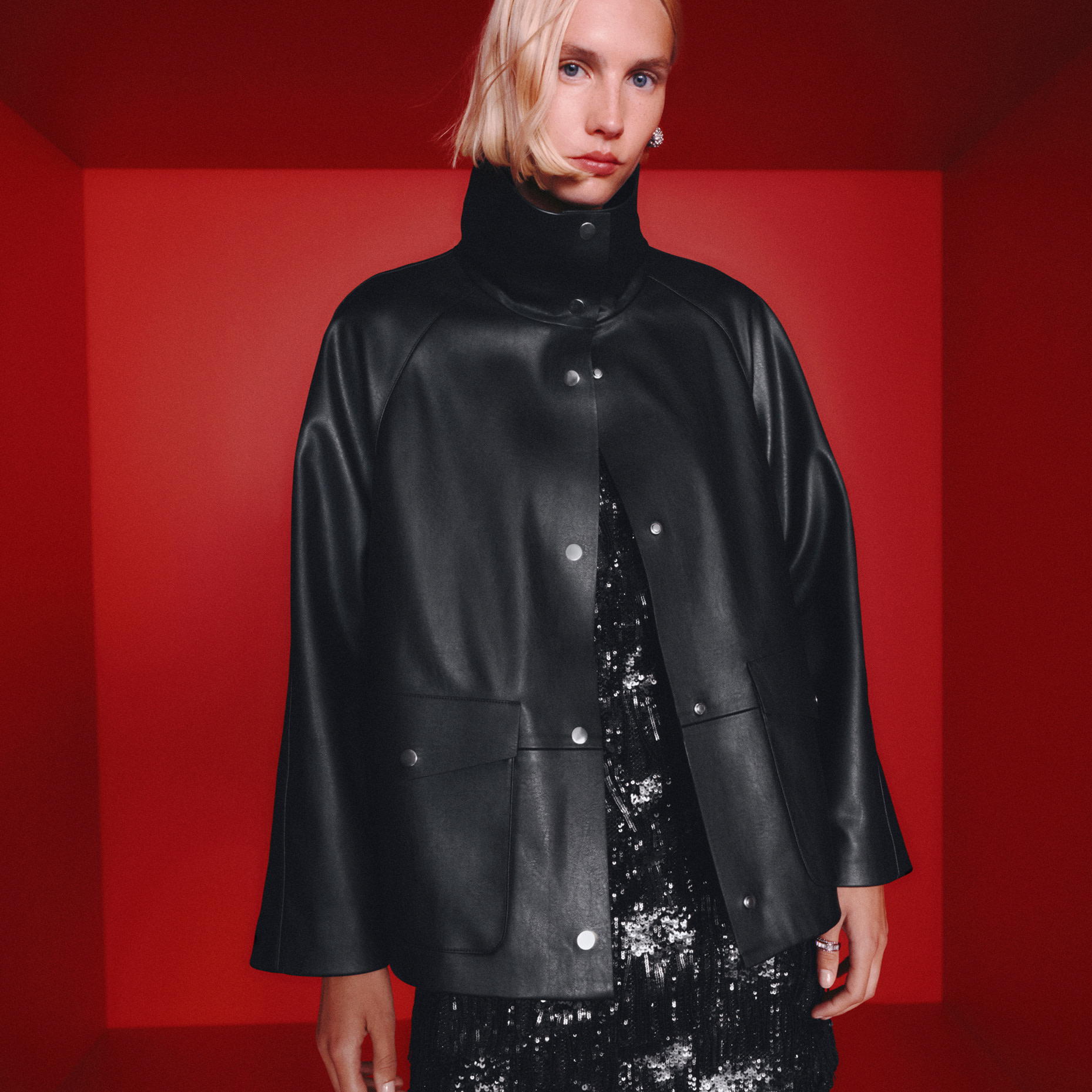 Woman in leather coat, red background