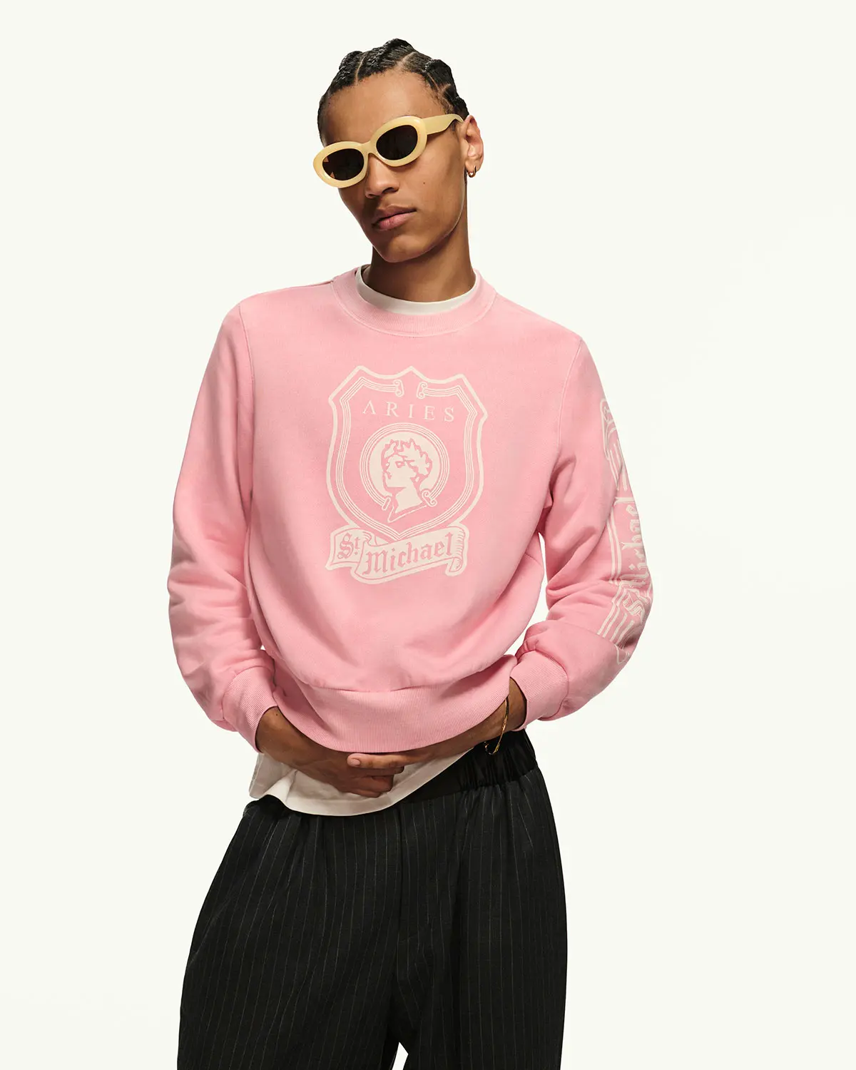 Man wearing pink sweatshirt with white logo print and black trousers