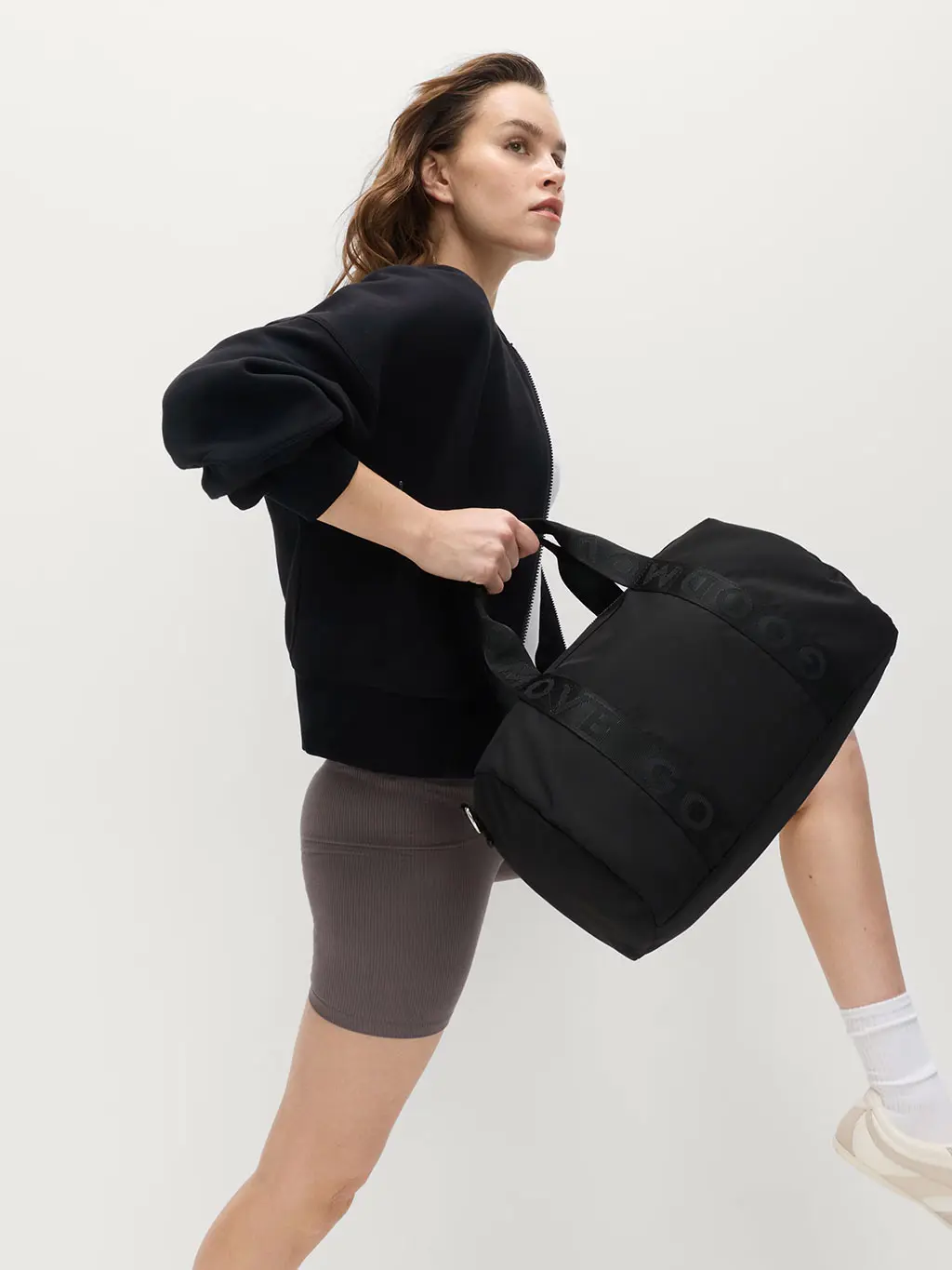 Woman wearing gym wear carrying a technical duffle bag
