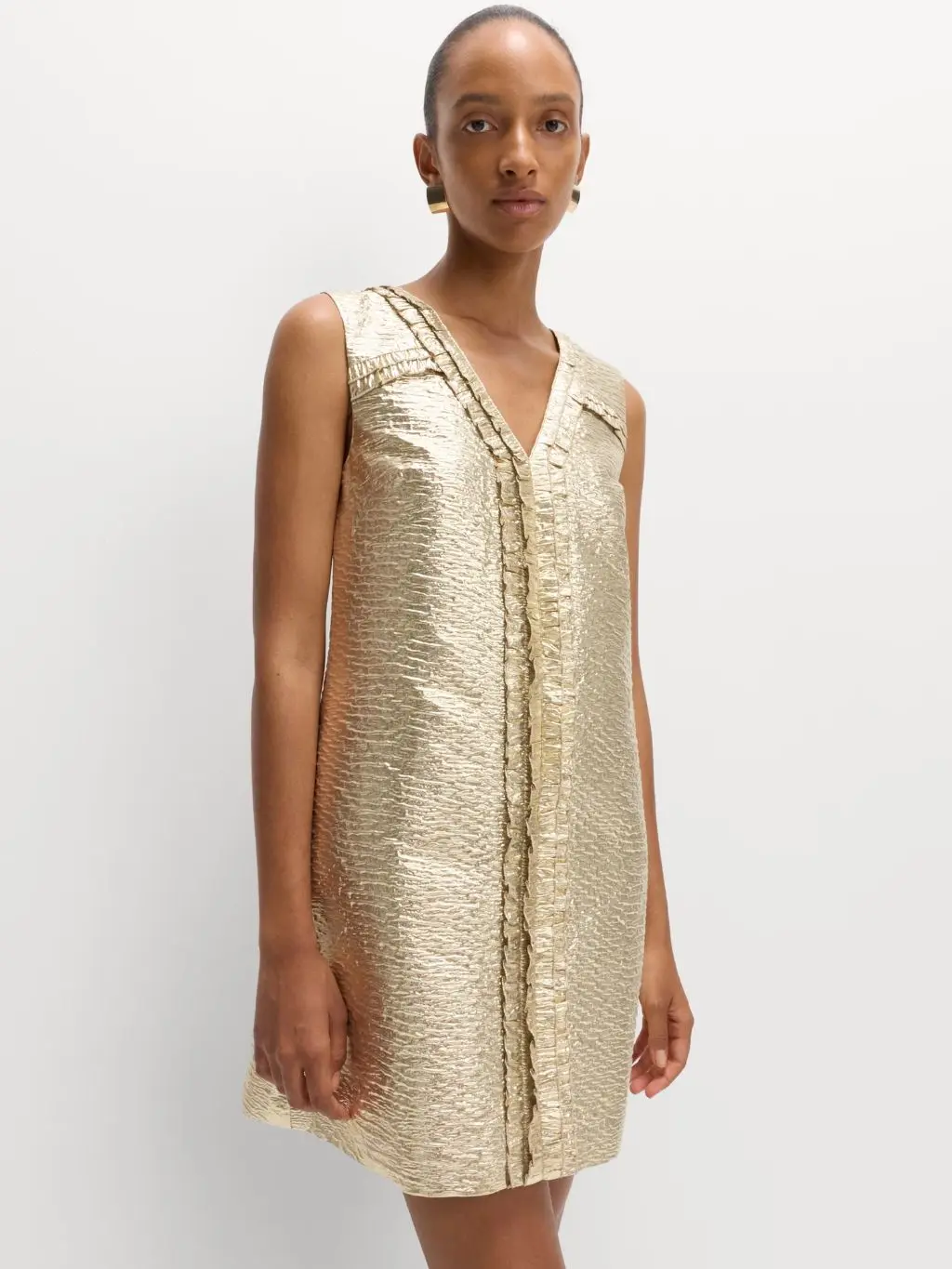 A woman wears a gold shift dress