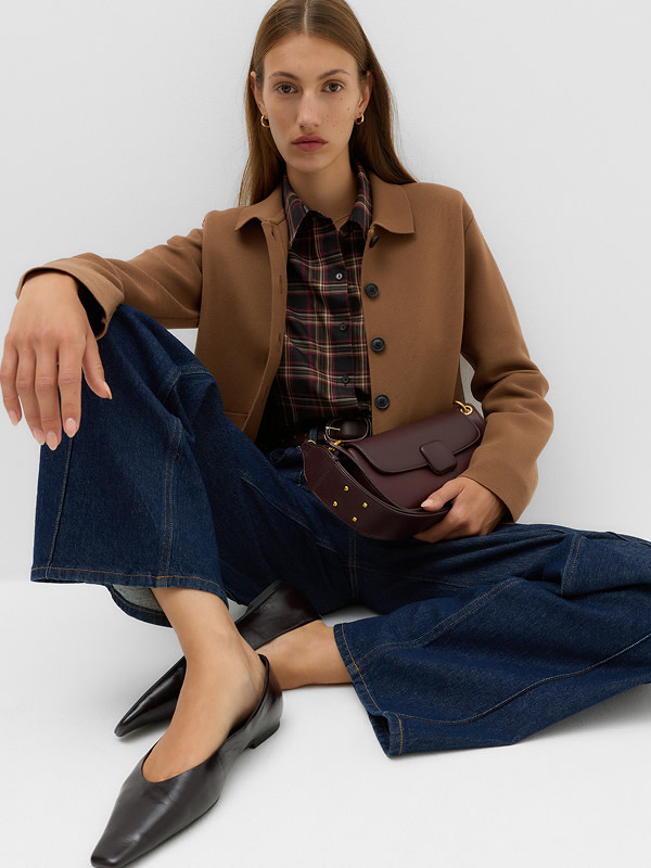 Woman wearing brown jacket over checked top and jeans