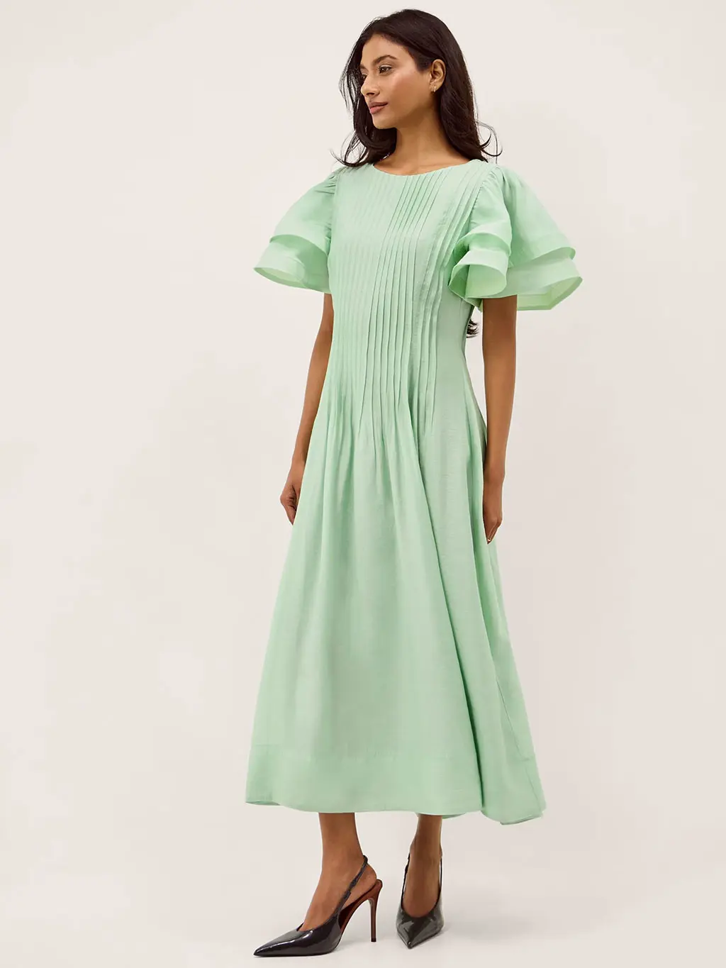 Woman wearing a green maxi dress with black stiletto heels