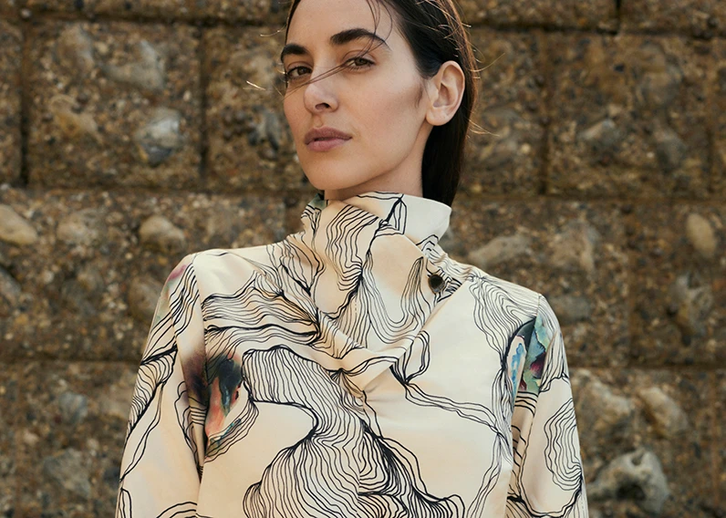 A woman wearing a printed cowl-neck dress by Jaeger
