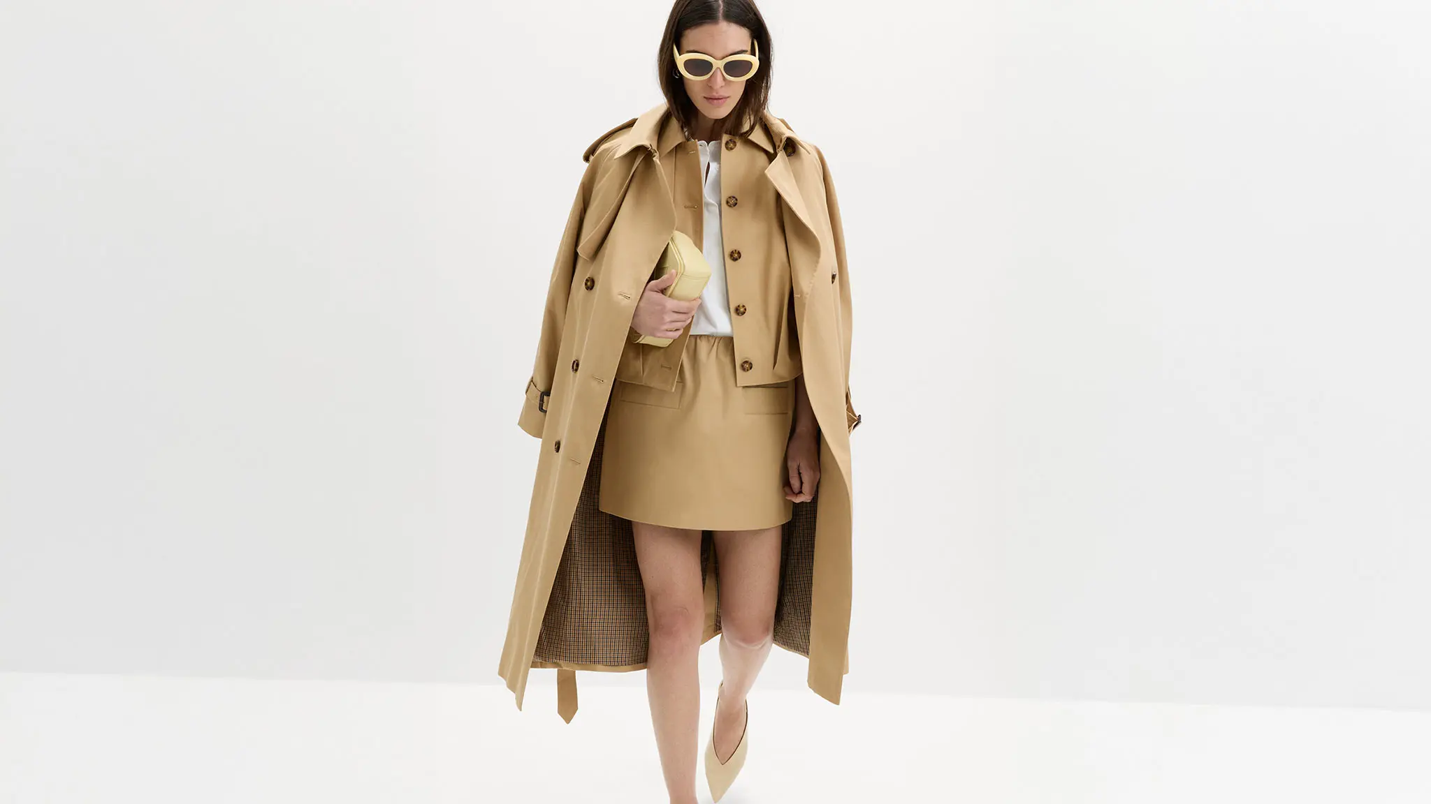Woman wearing a balloon-sleeve jacket with a white shirt, coordinating skirt, long trench, and yellow accessories