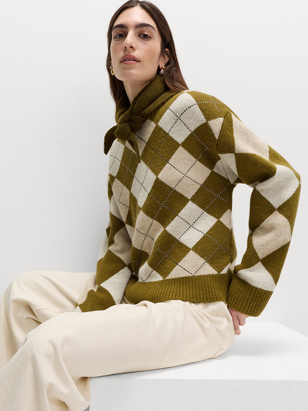 Woman wearing a green argyle jumper with cream trousers