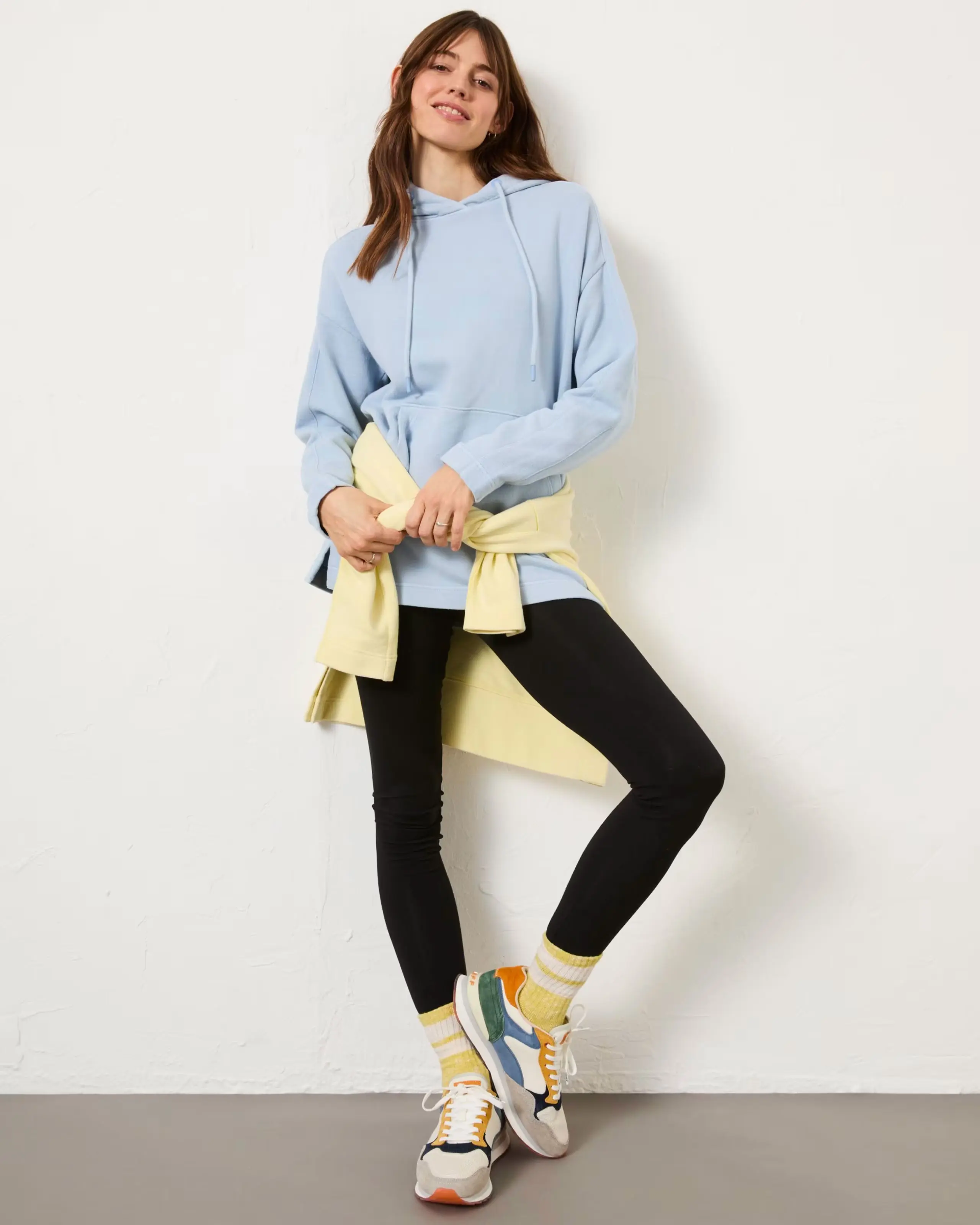 Woman wearing blue hoodie, black leggings and colourful trainers