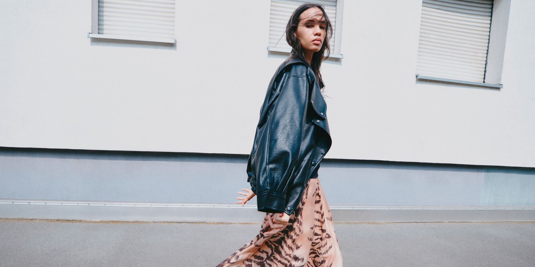 Woman wearing leather jacket over printed dress