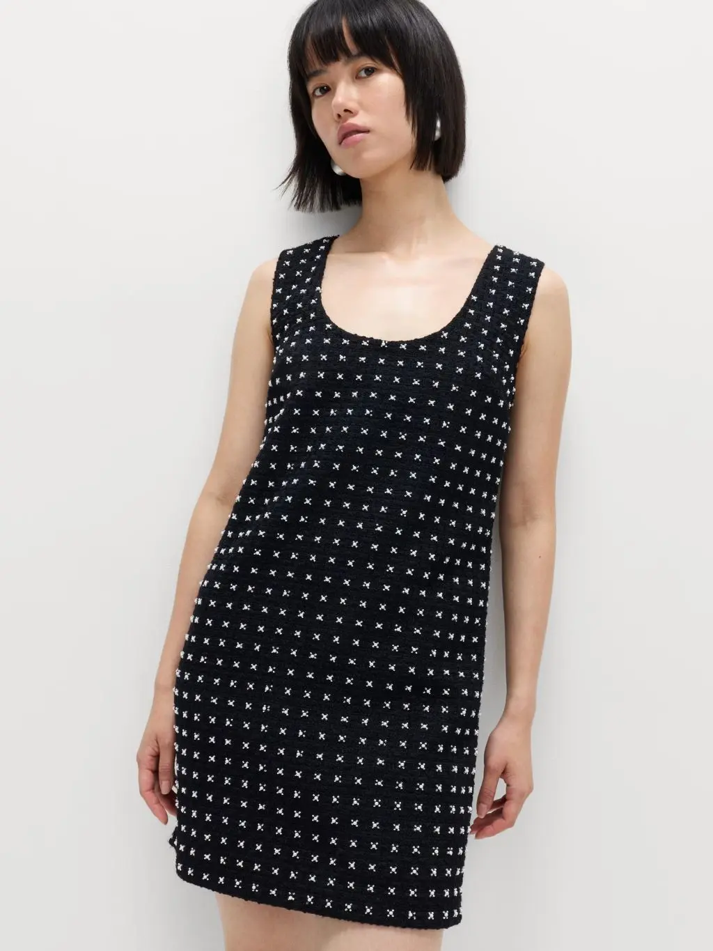 A woman wears an embellished black mini shift dress