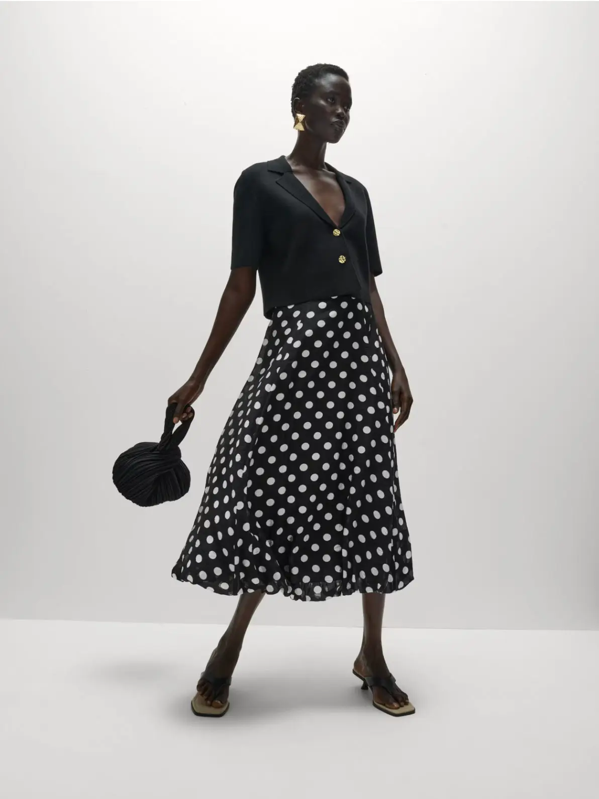 Woman wearing black top, polka dot skirt and heels