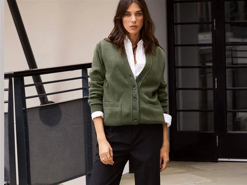 Woman wearing white shirt under green cardigan with black trousers