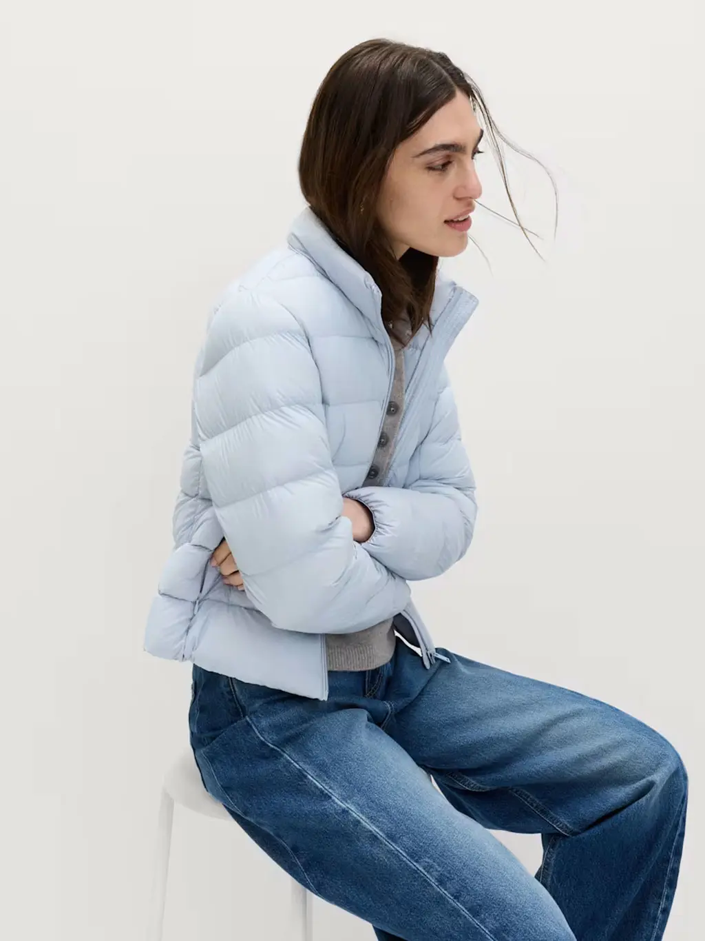 Woman wearing a light blue puffer jacket with blue barrel-leg jeans