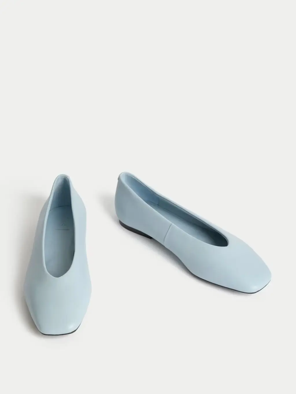 Cut-outs of pale blue ballet pumps on a white surface