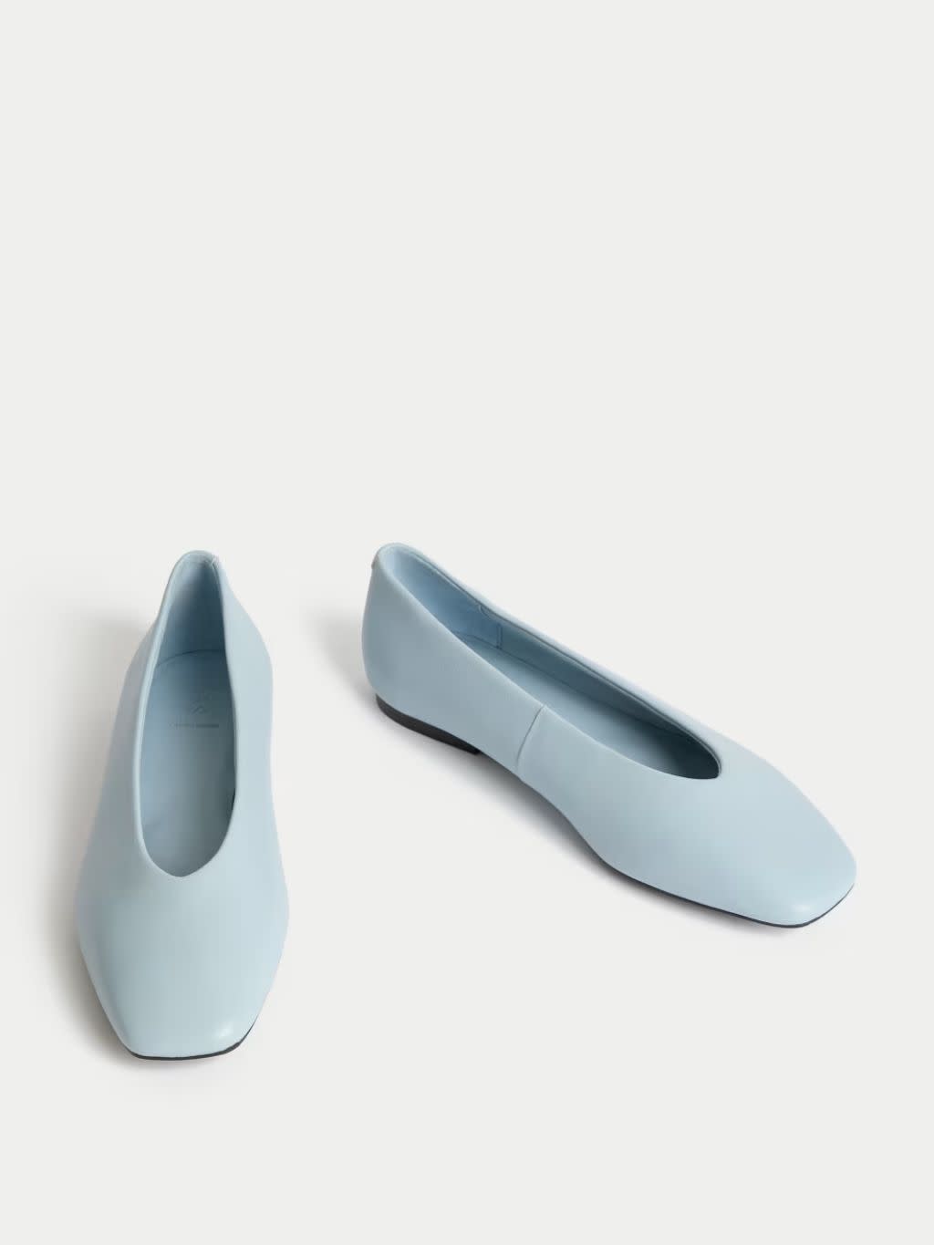 Cut-outs of pale blue ballet pumps on a white surface