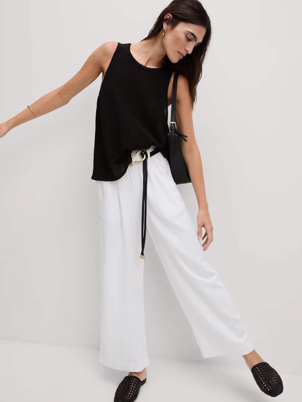 Woman wearing white linen trousers with a black top and sandals