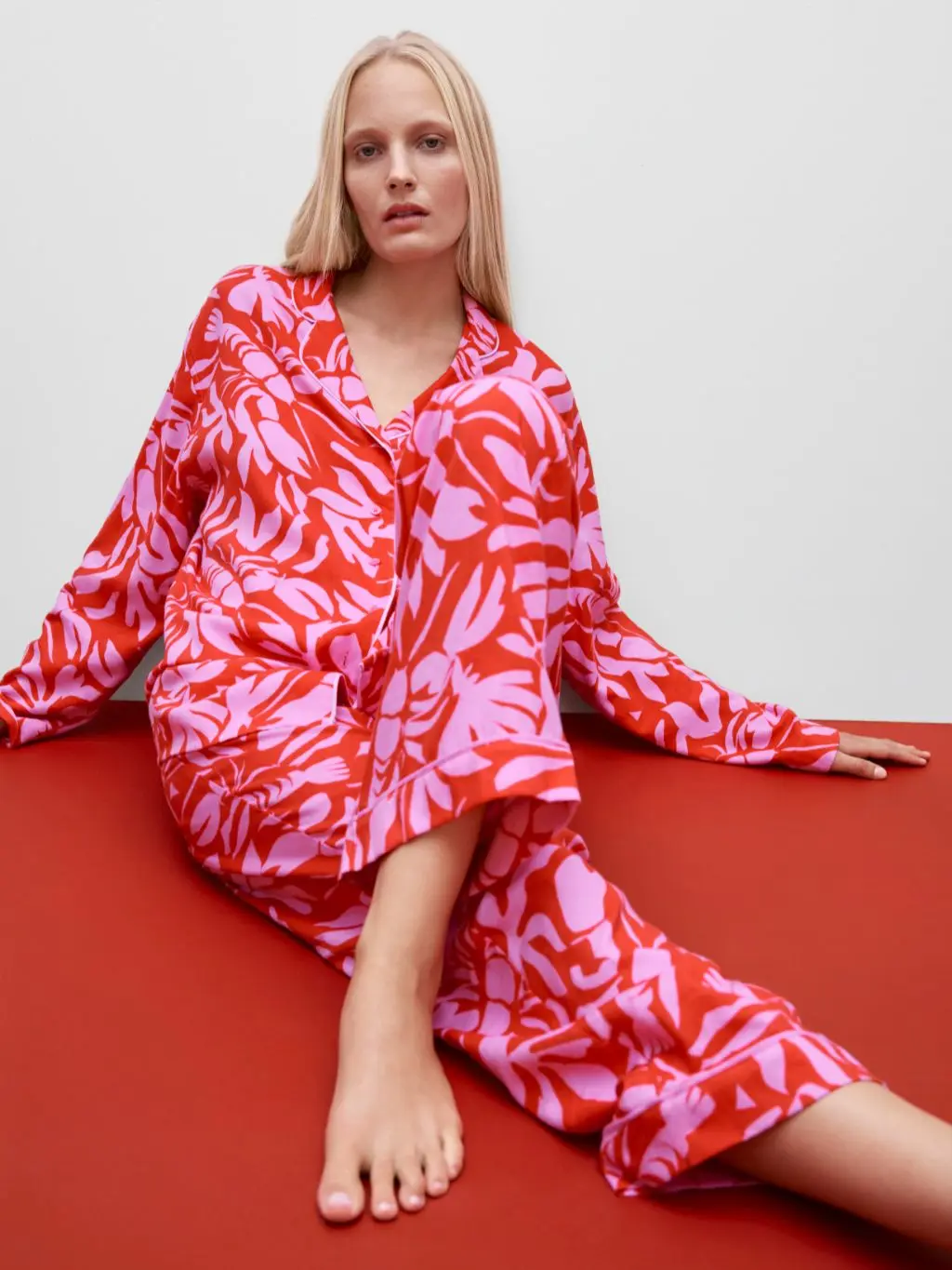 A woman wearing red and pink pyjamas sat on a red carpet