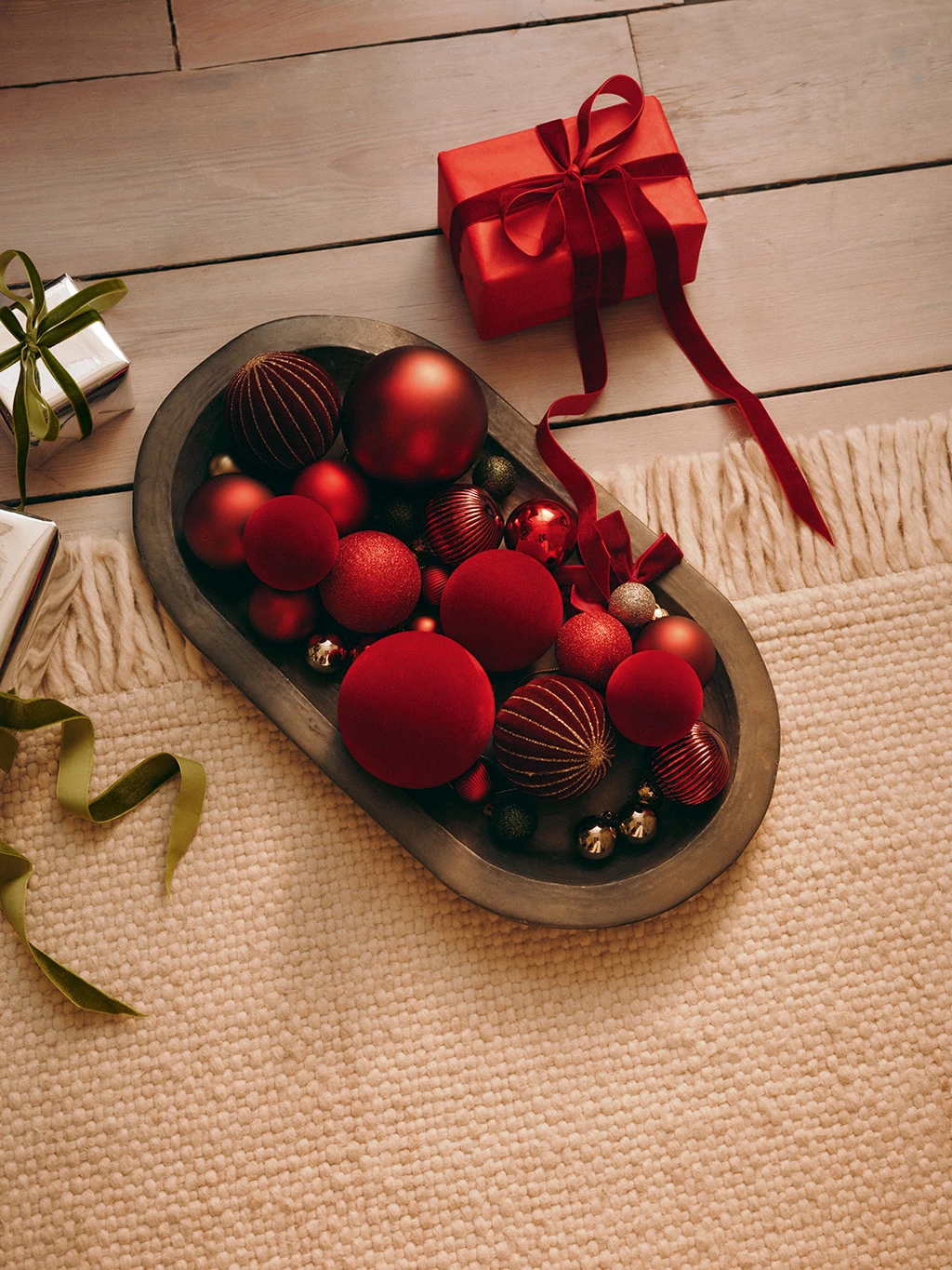 Group of red baubles on a brown oval tray.