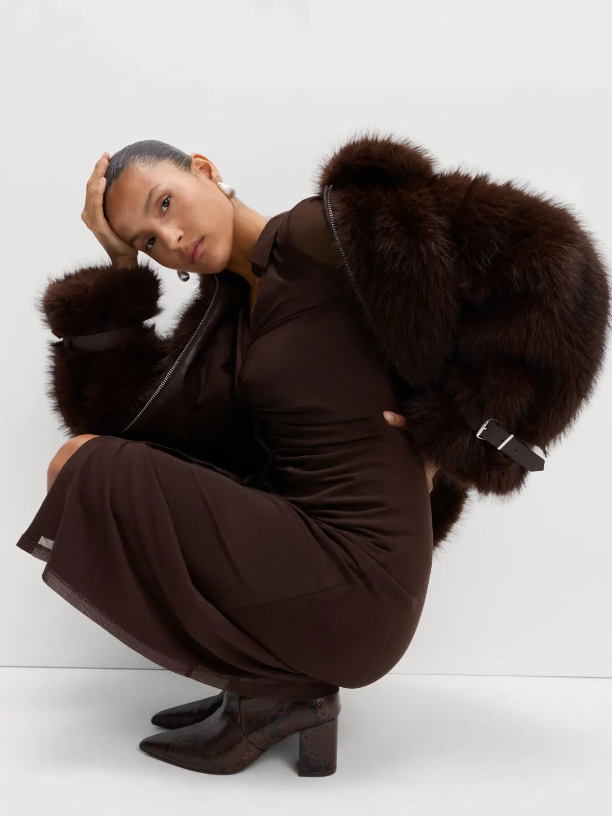 Woman wearing long brown dress, brown faux-fur coat and brown heeled boots