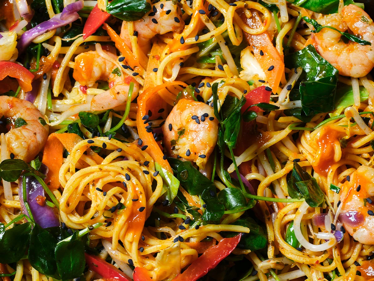 A close-up image of a stir fry with colourful vegetables and prawns 