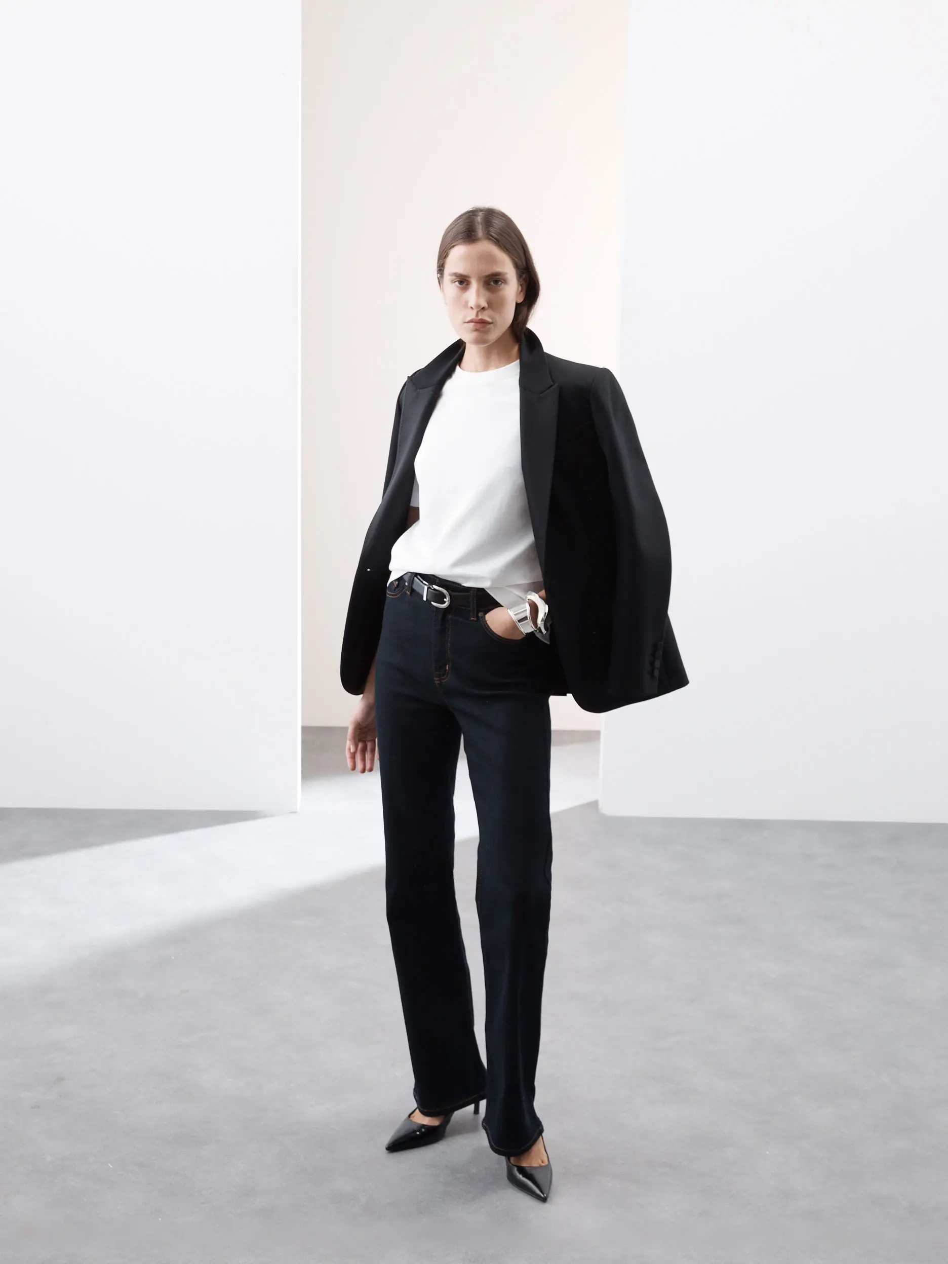 Woman wearing a white T-shirt, black blazer, jeans and heels