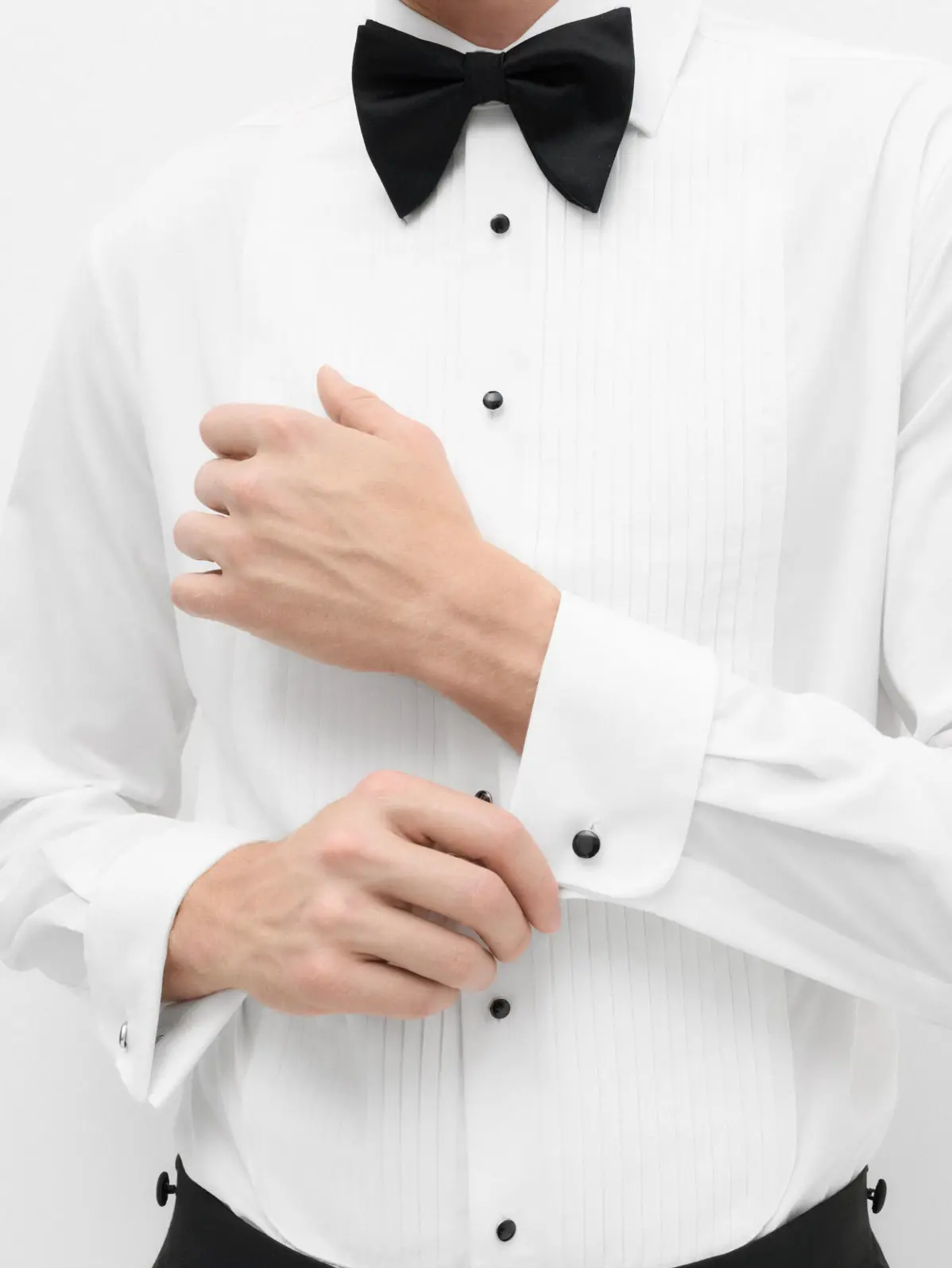 Man wearing white dress shirt with black buttons and black bow tie 
