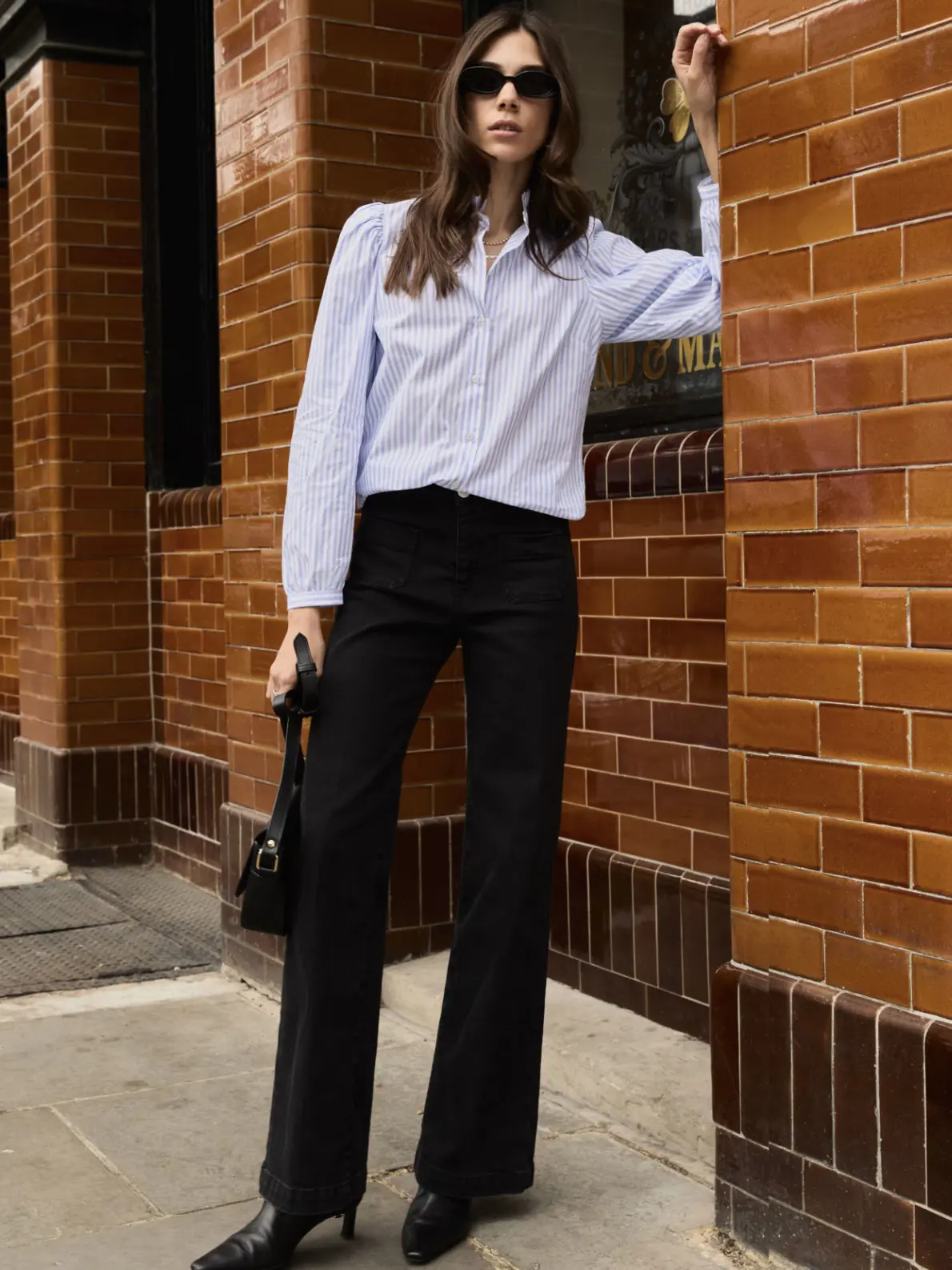 Woman wearing white shirt, black jeans, heeled boots and sunglasses