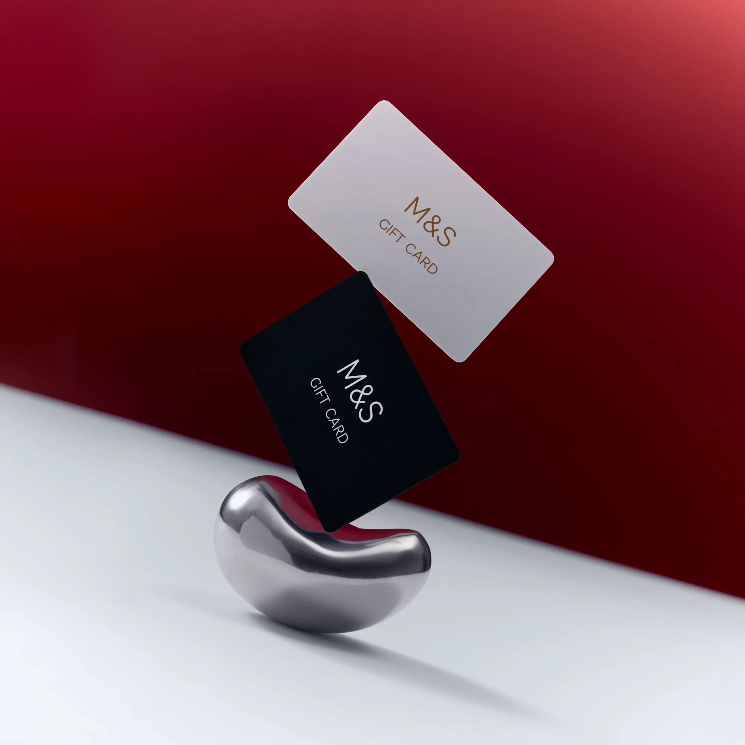 White and black gift cards balancing on a silver podium against a red backdrop