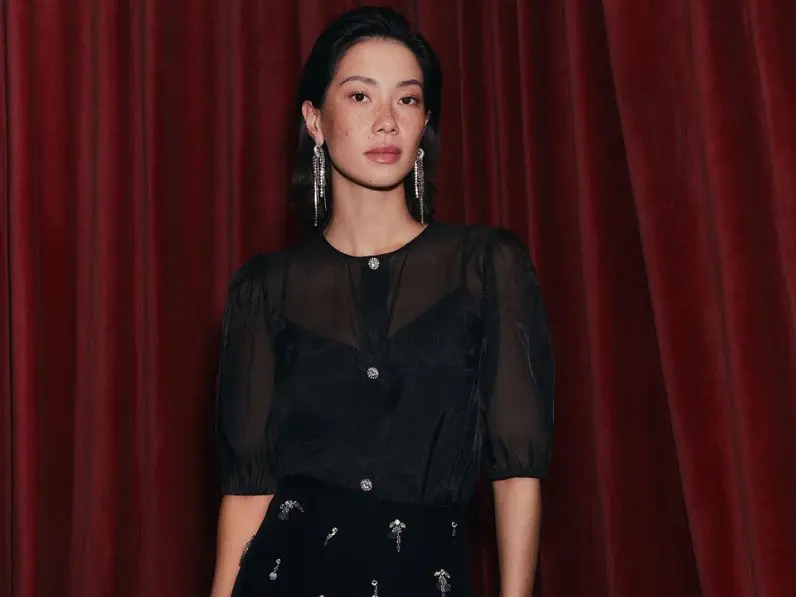 Woman wearing black sheer top, black embellished mini skirt and statement silver earrings 