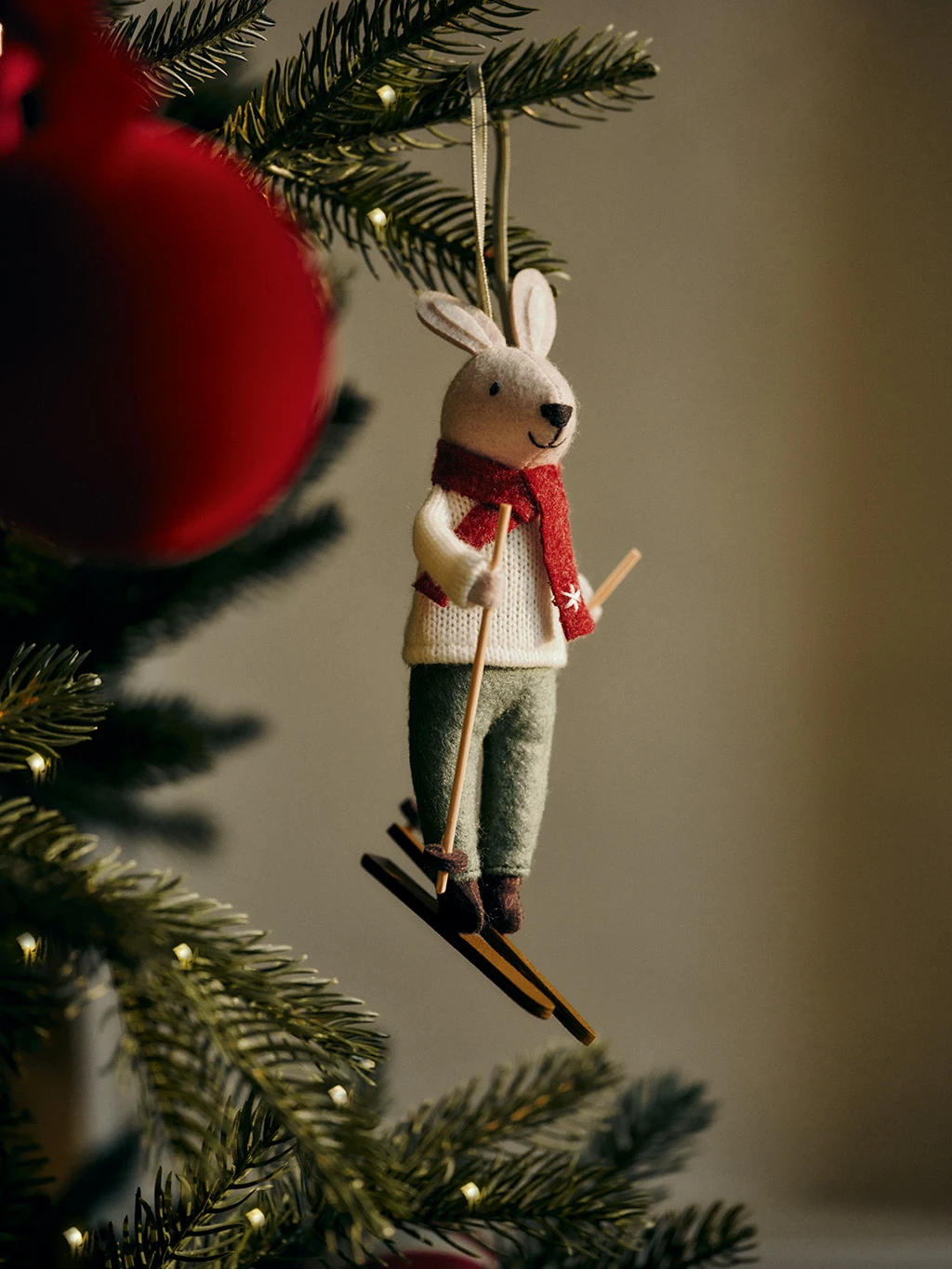Felted mouse Christmas tree decoration with skis and a red scarf.