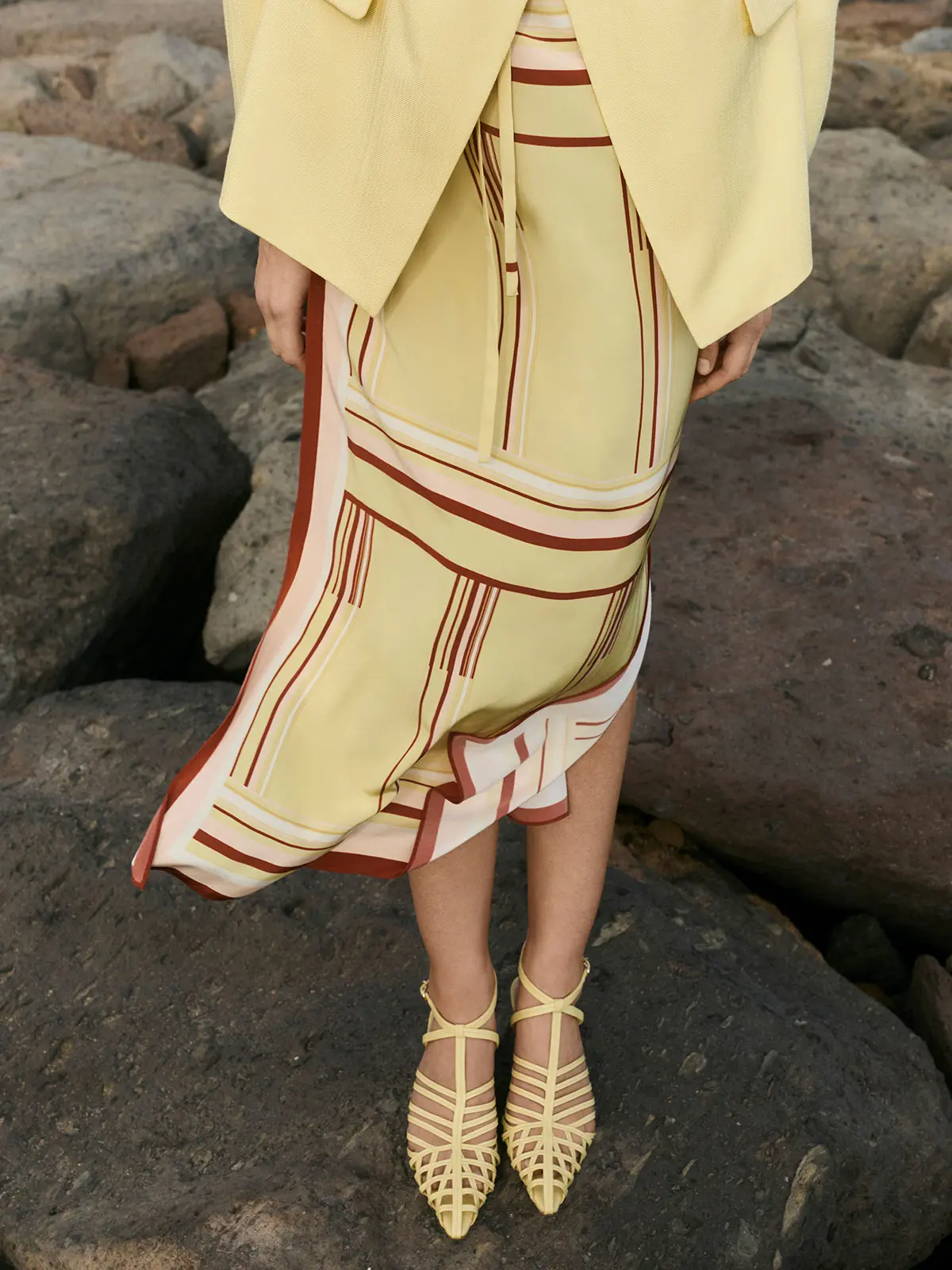 Woman wearing yellow and red patterned dress and yellow sandals 