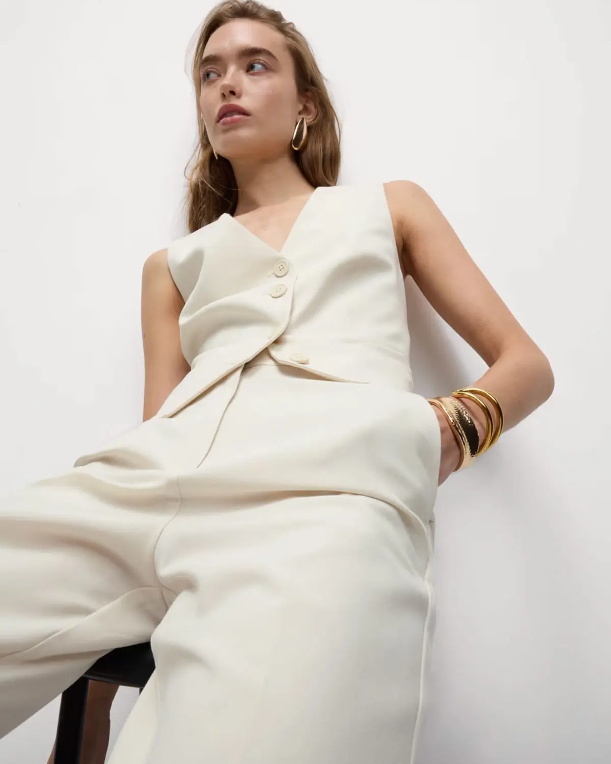 Woman wearing a white waistcoat with coordinating trousers and gold jewellery