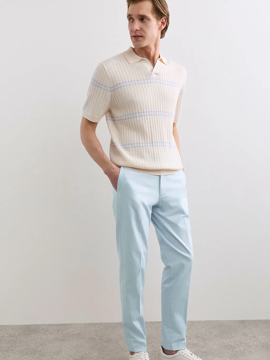 Man in blue trousers and striped knit top