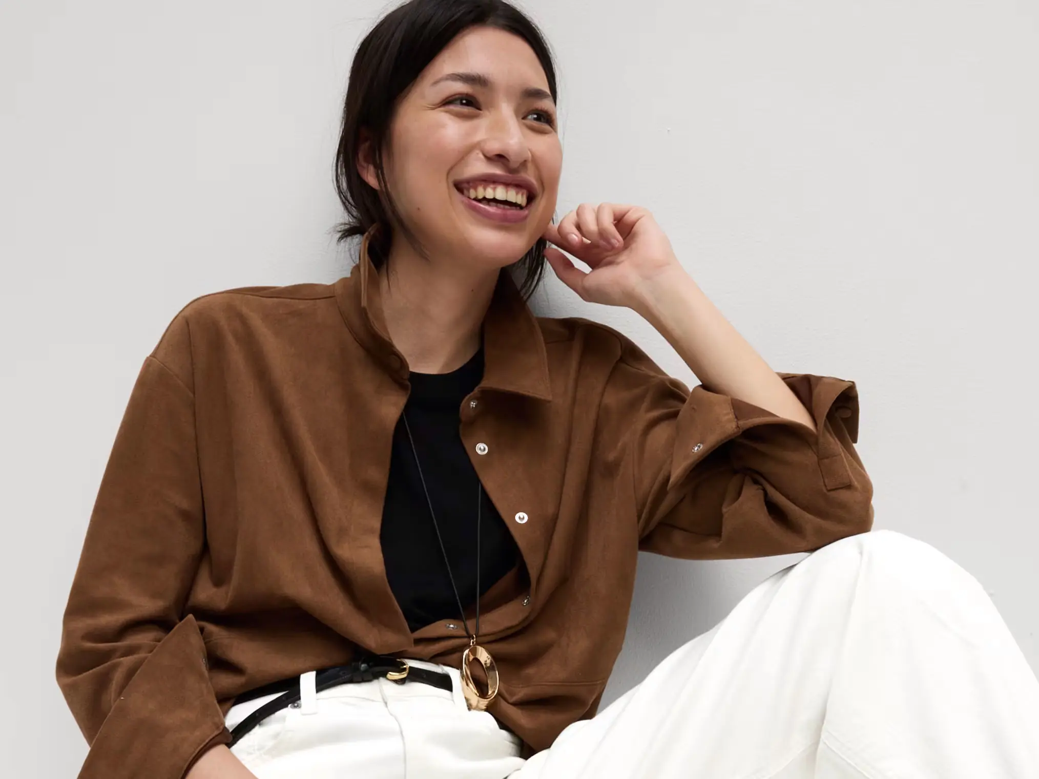 Woman wearing a brown shirt and white wide leg jeans