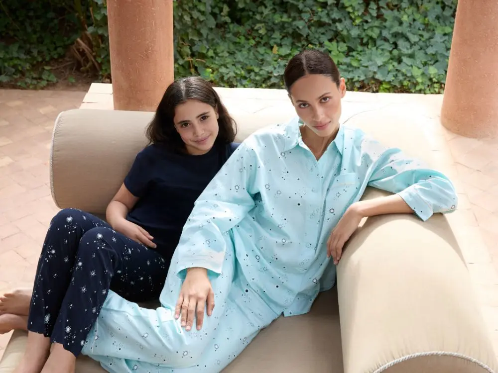 A mother and daughter sat on a sofa in blue pyjamas