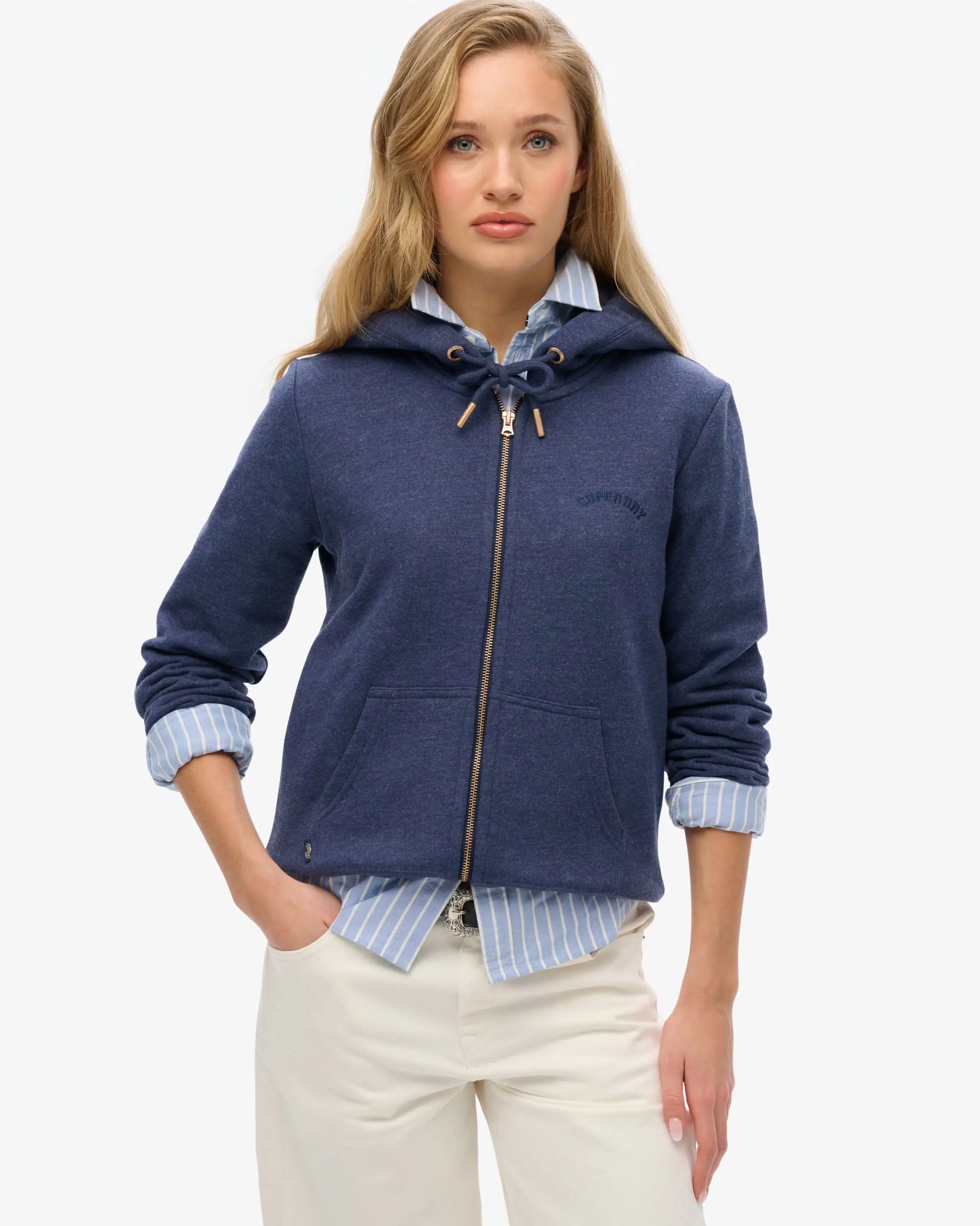 Woman wearing navy hoodie over blue shirt with cream jeans