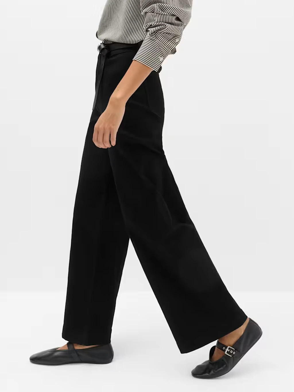 Close up of a model's legs wearing black trousers and black Mary Jane shoes.