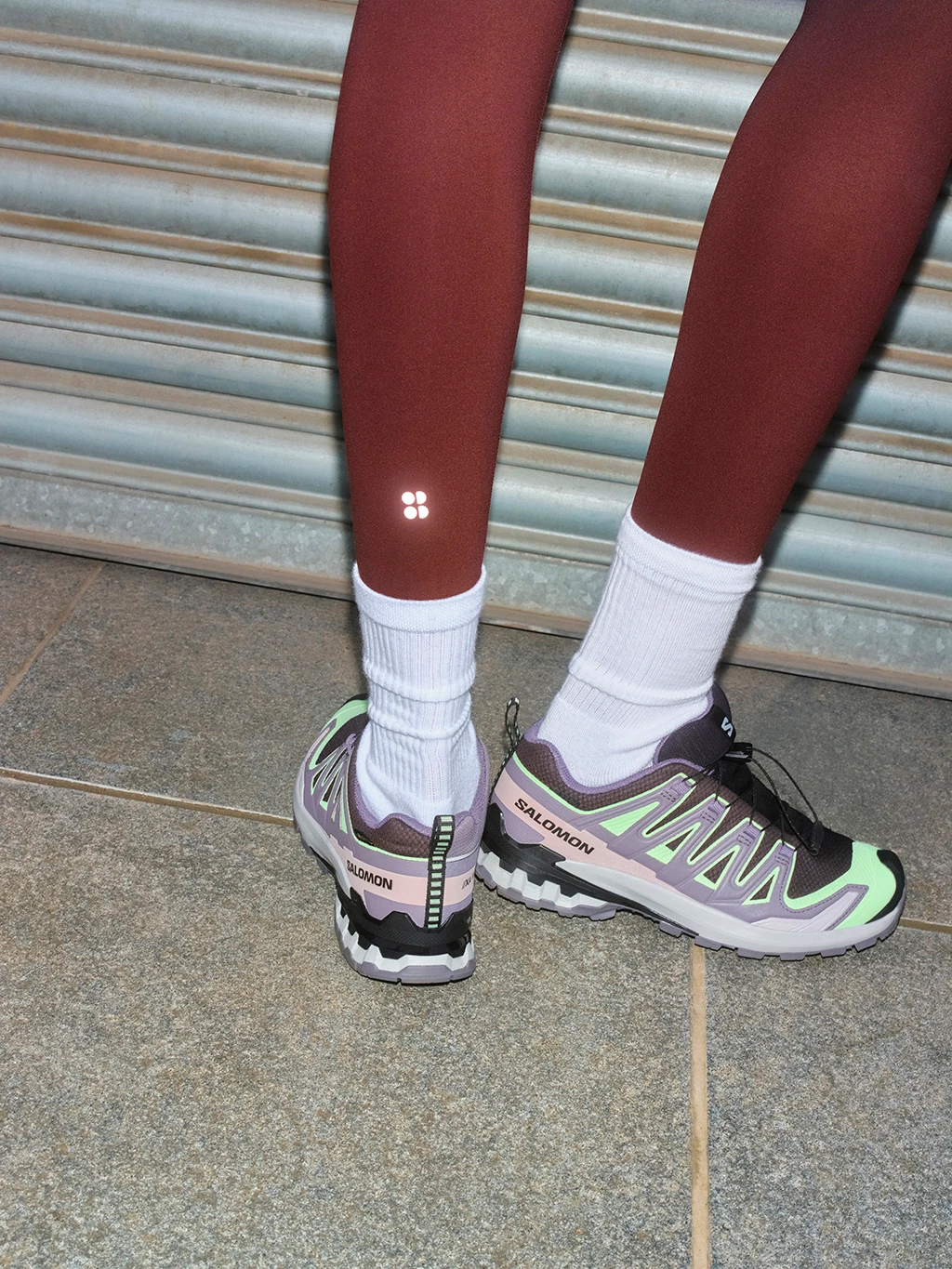 Woman wearing grey and neon green Salomon running trainers with white socks