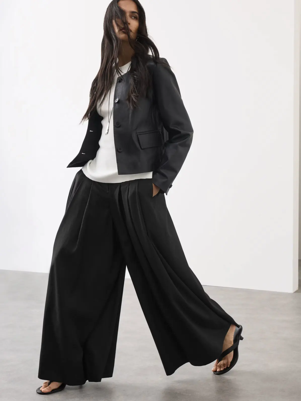 Woman wearing a white top, leather jacket, black culottes and kitten heels 