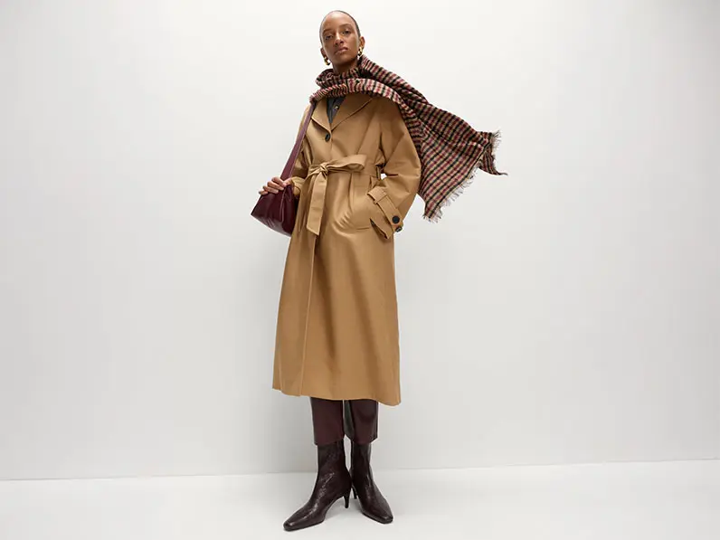 Woman wearing a checked scarf with a trench coat and boots