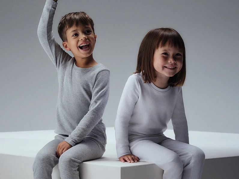 Two children in matching grey and white thermal sets.