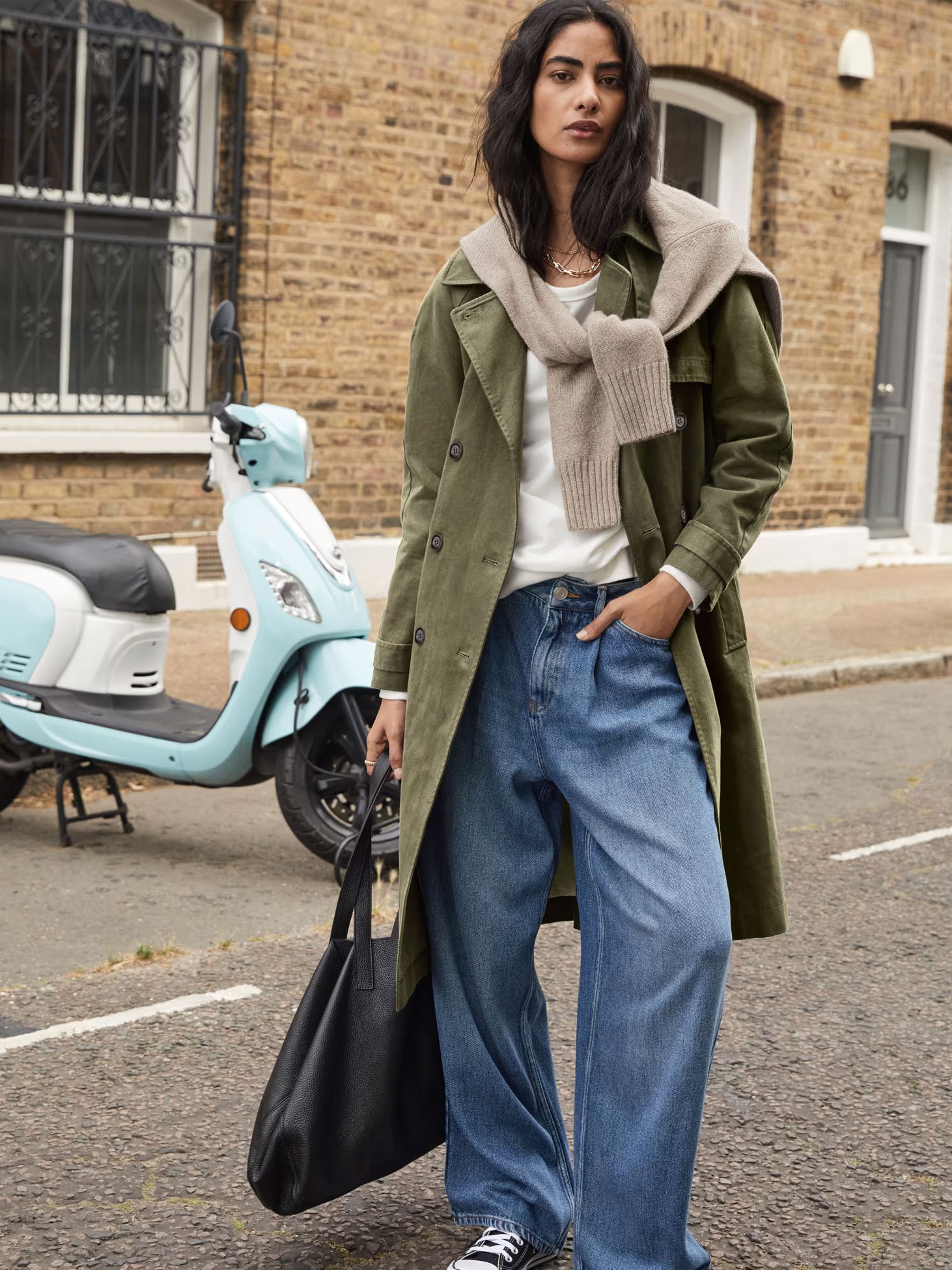 Woman wearing green trench coat and blue wide-leg jeans. Shop wide-leg jeans