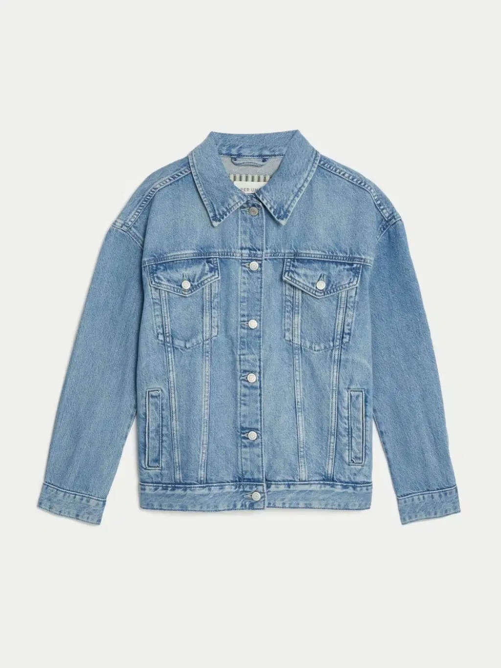 A cutout of a pale blue oversized denim jacket on a cream background