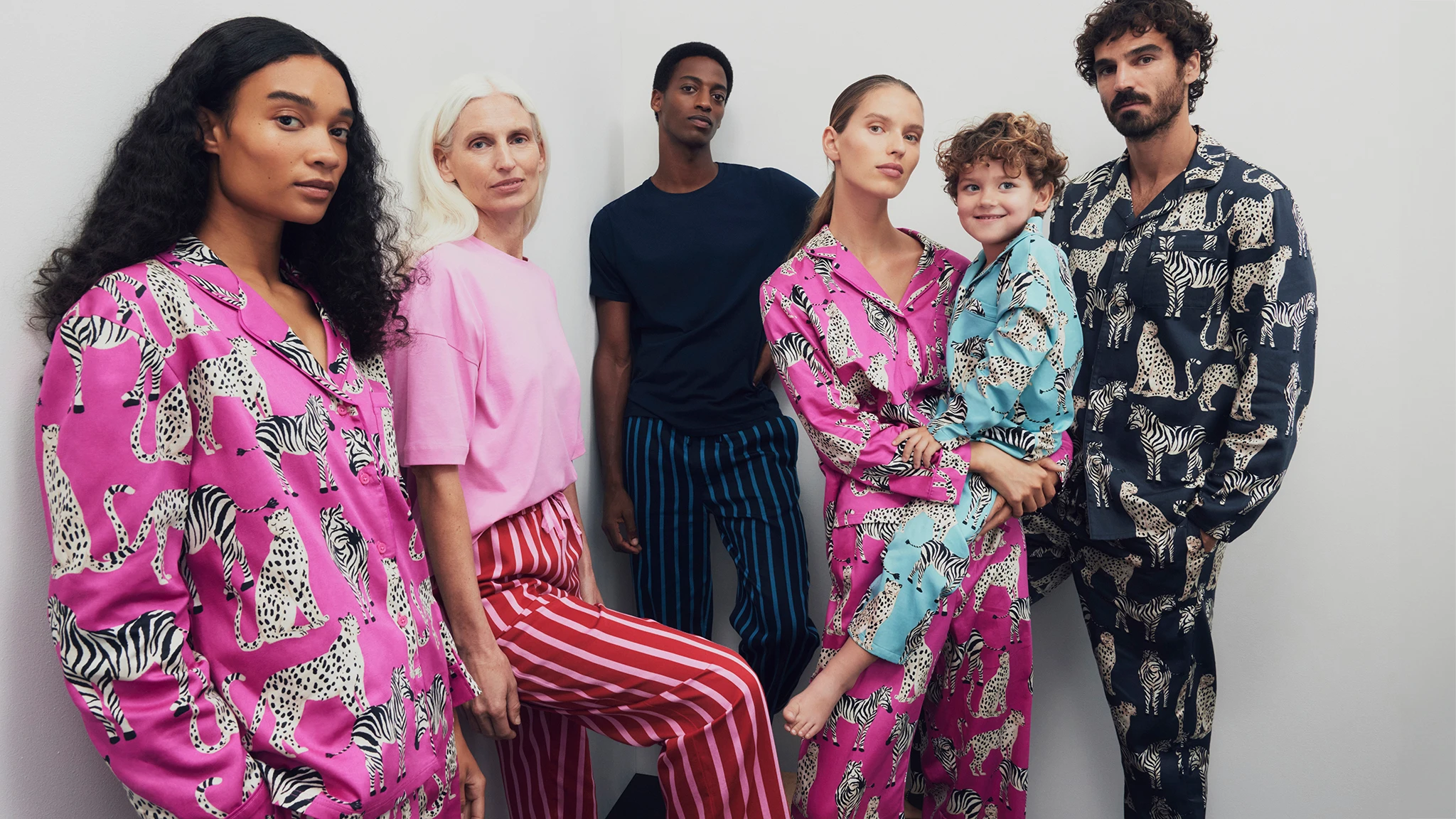 Three women, two men and a boy wearing assortment of matching Christmas family pyjamas