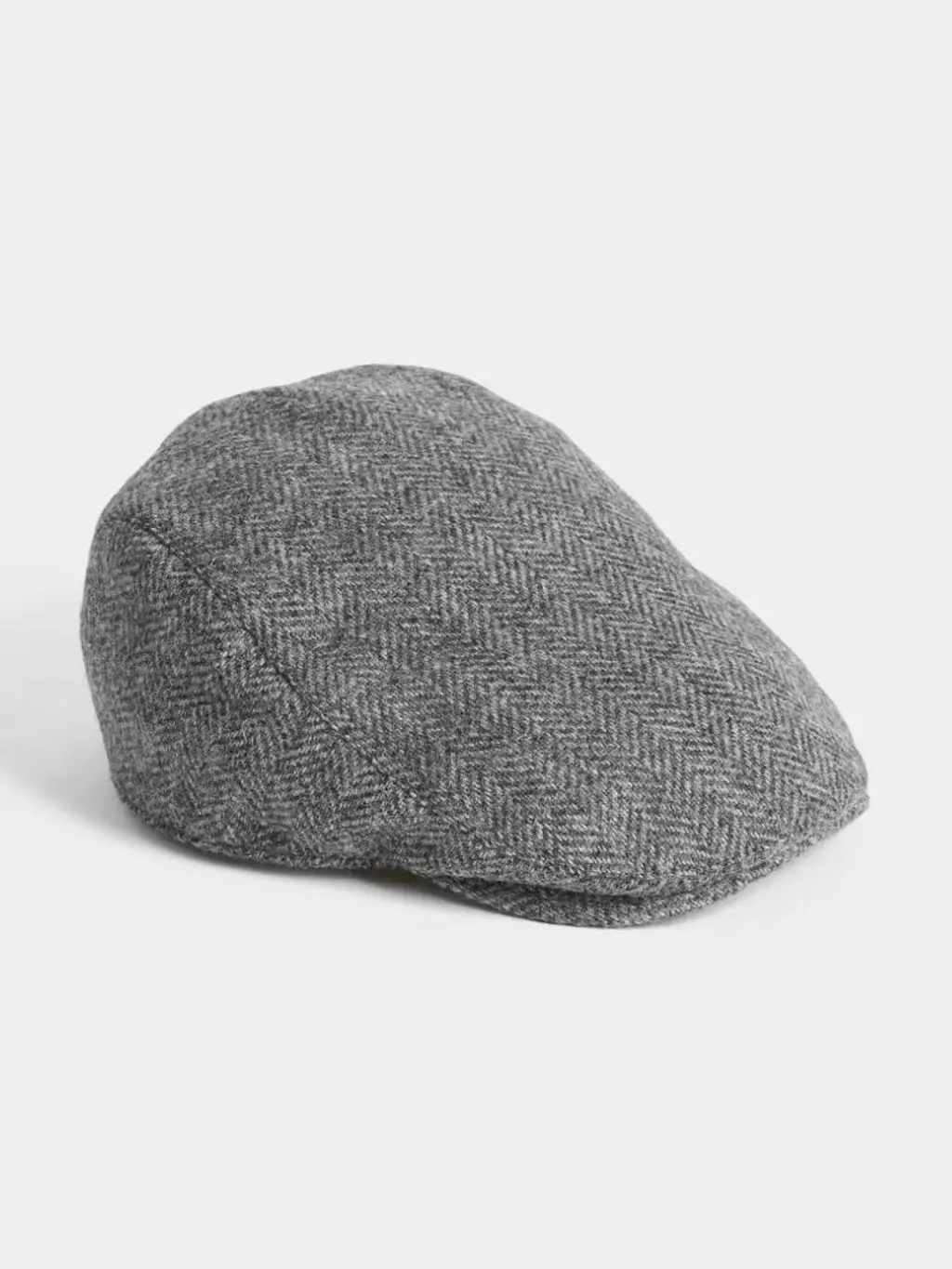 A cut out shot of a tweed flat cap shot against a light background