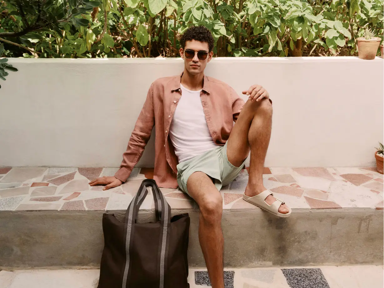 Man wearing summer outfit including a shirt, shorts and sandals 