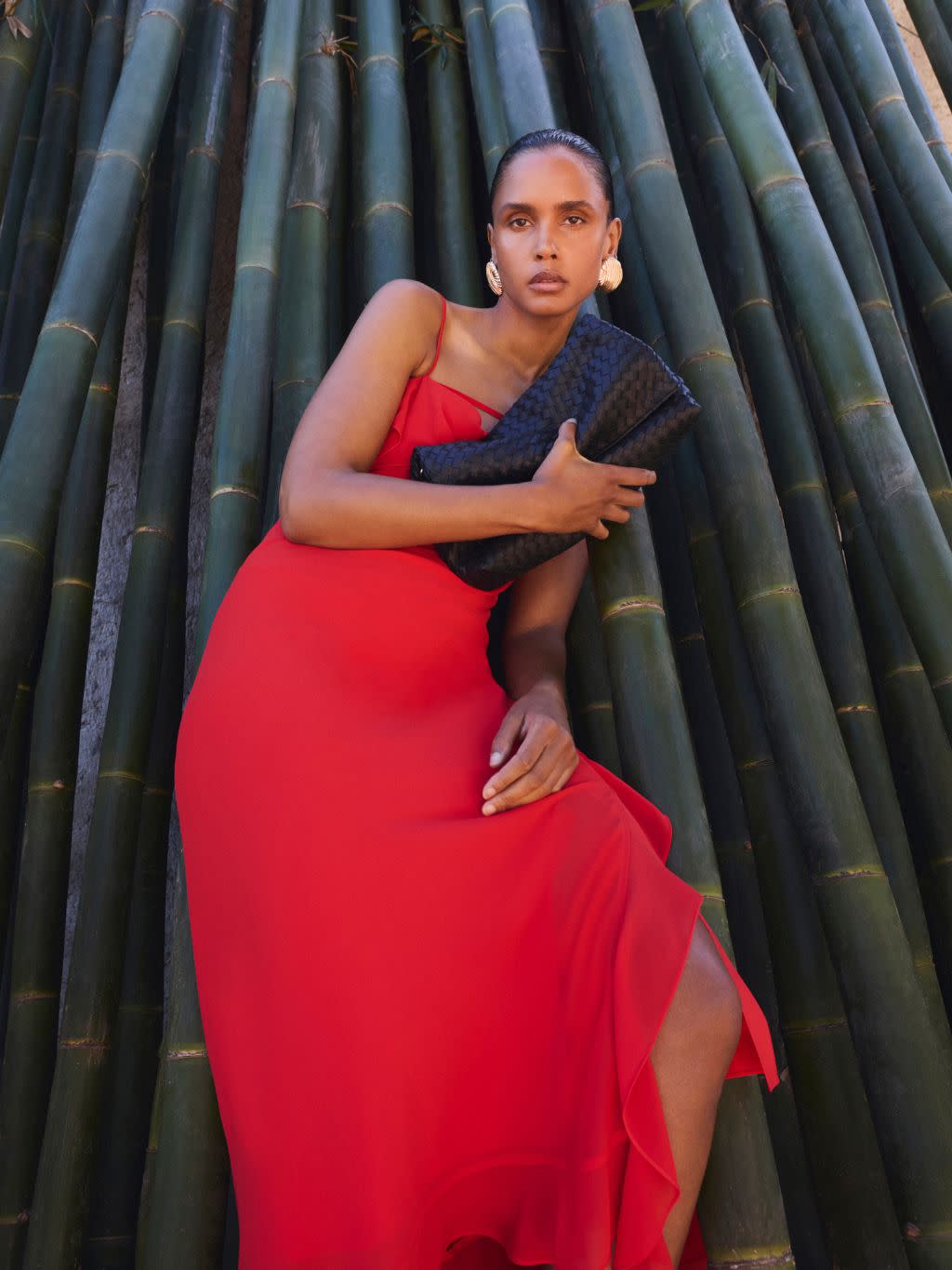 A woman wears a bright red cowl neck dress