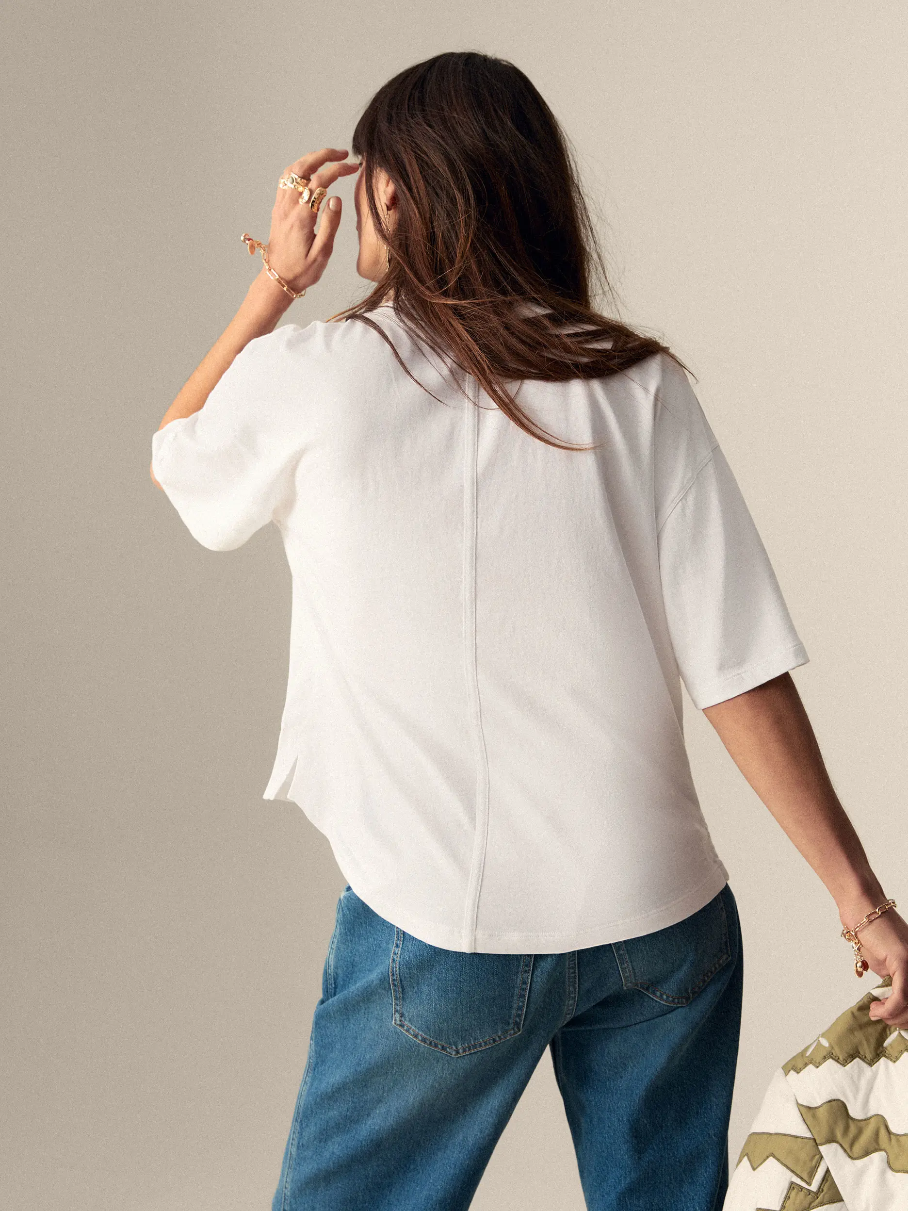 Woman wearing a seam detail white T-shirt and jeans, facing away from the camera