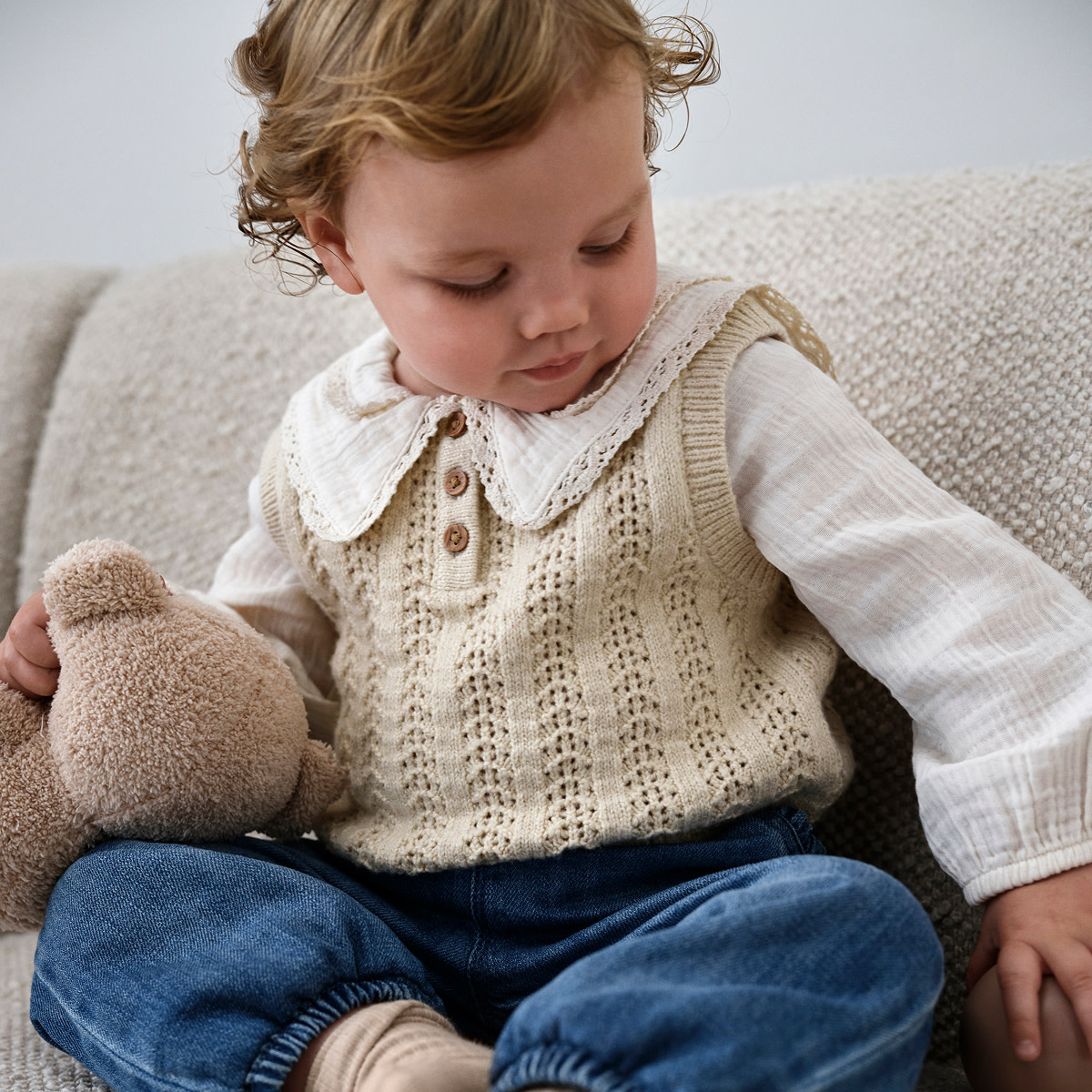 Baby wearing a collared blouse with knitwear and jeans