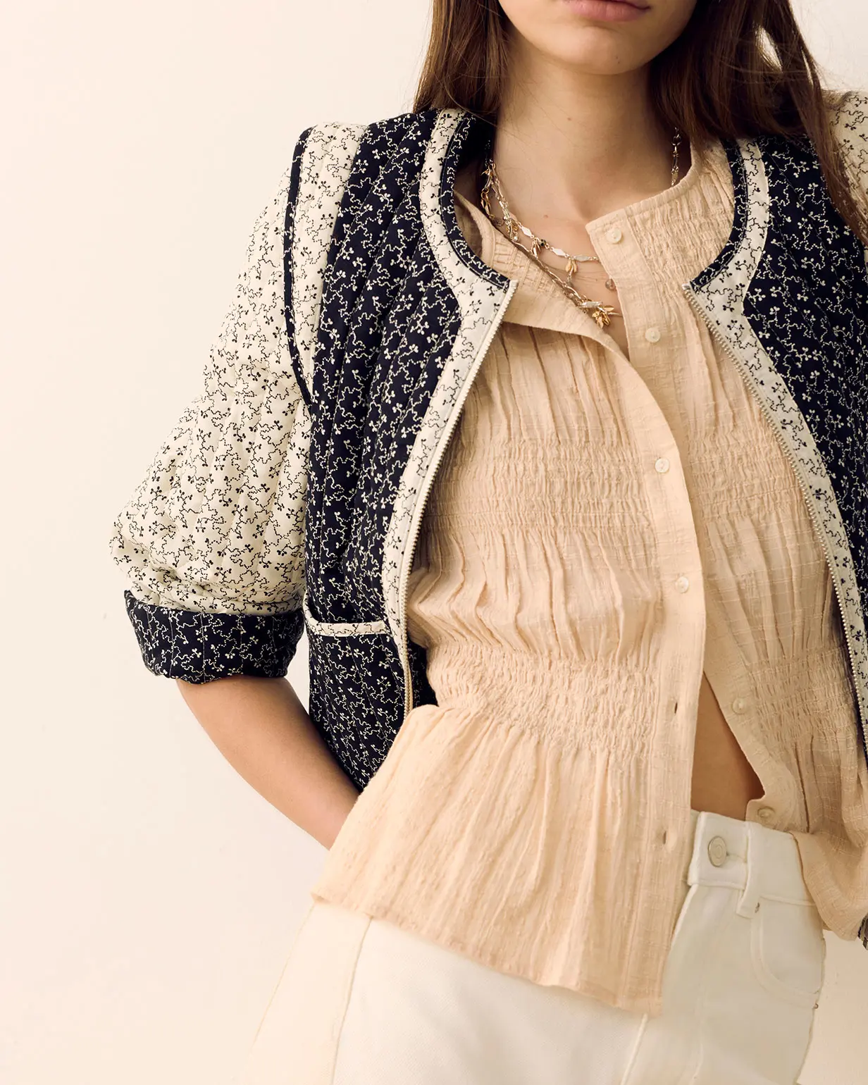 Woman wearing navy quilted jacket, ecru jeans and a cream shirt