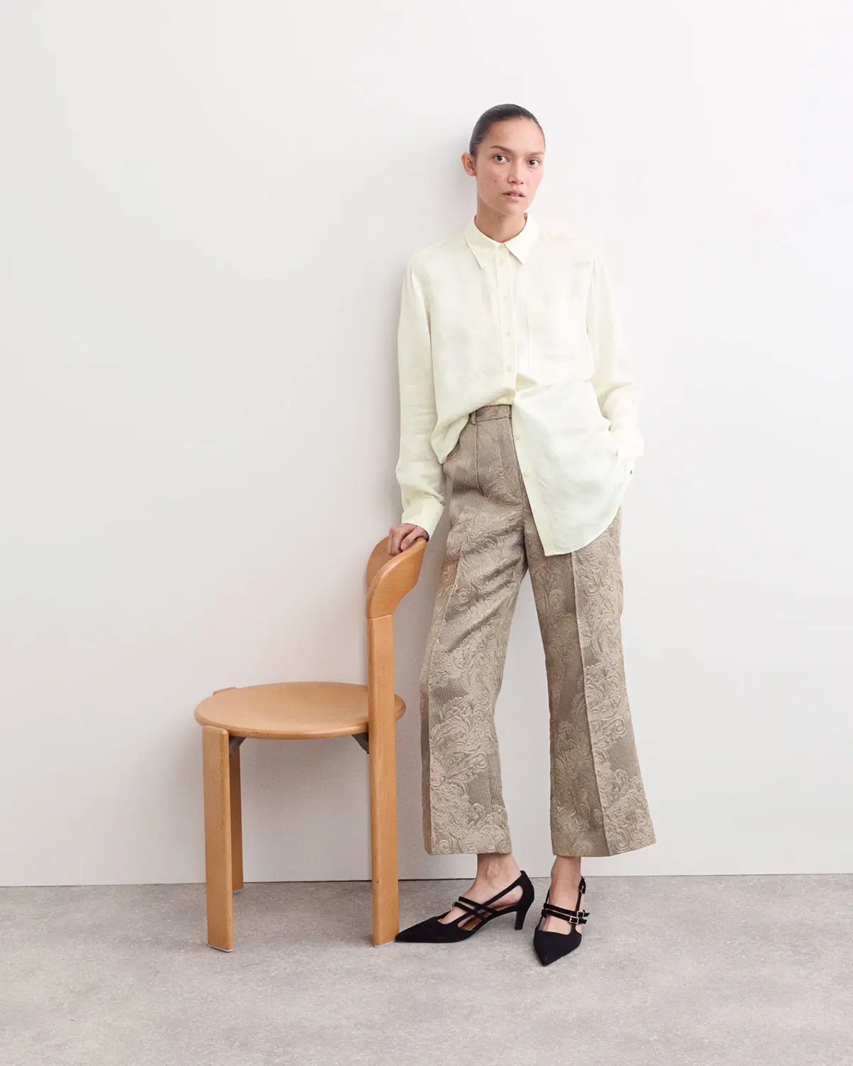 Woman wearing cream shirt and brown jacquard trousers by Jaeger